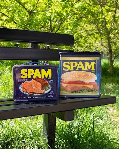 Hand holding a can of SPAM through a blue background