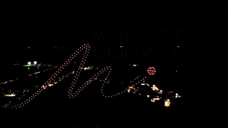 Nighttime drone light display spelling out 'Happy New Year' with decorative elements.