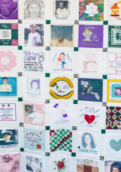 A quilt composed of various fabric squares with embroidered and printed images, personal messages, and decorative patterns.