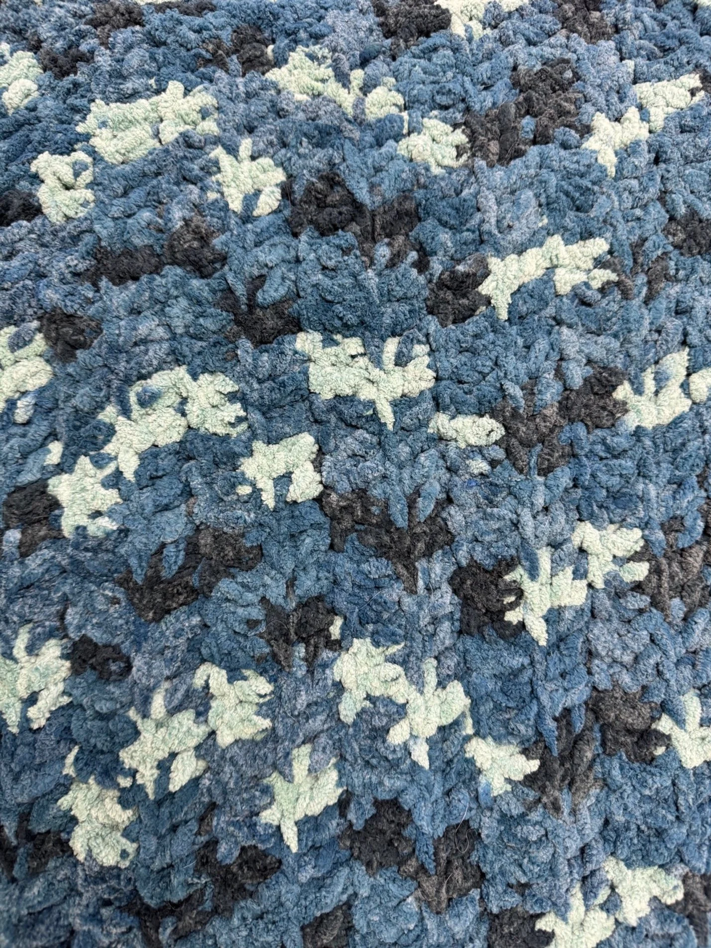 Close-up of a textured multicolored carpet with a pattern of blue, black, and white.