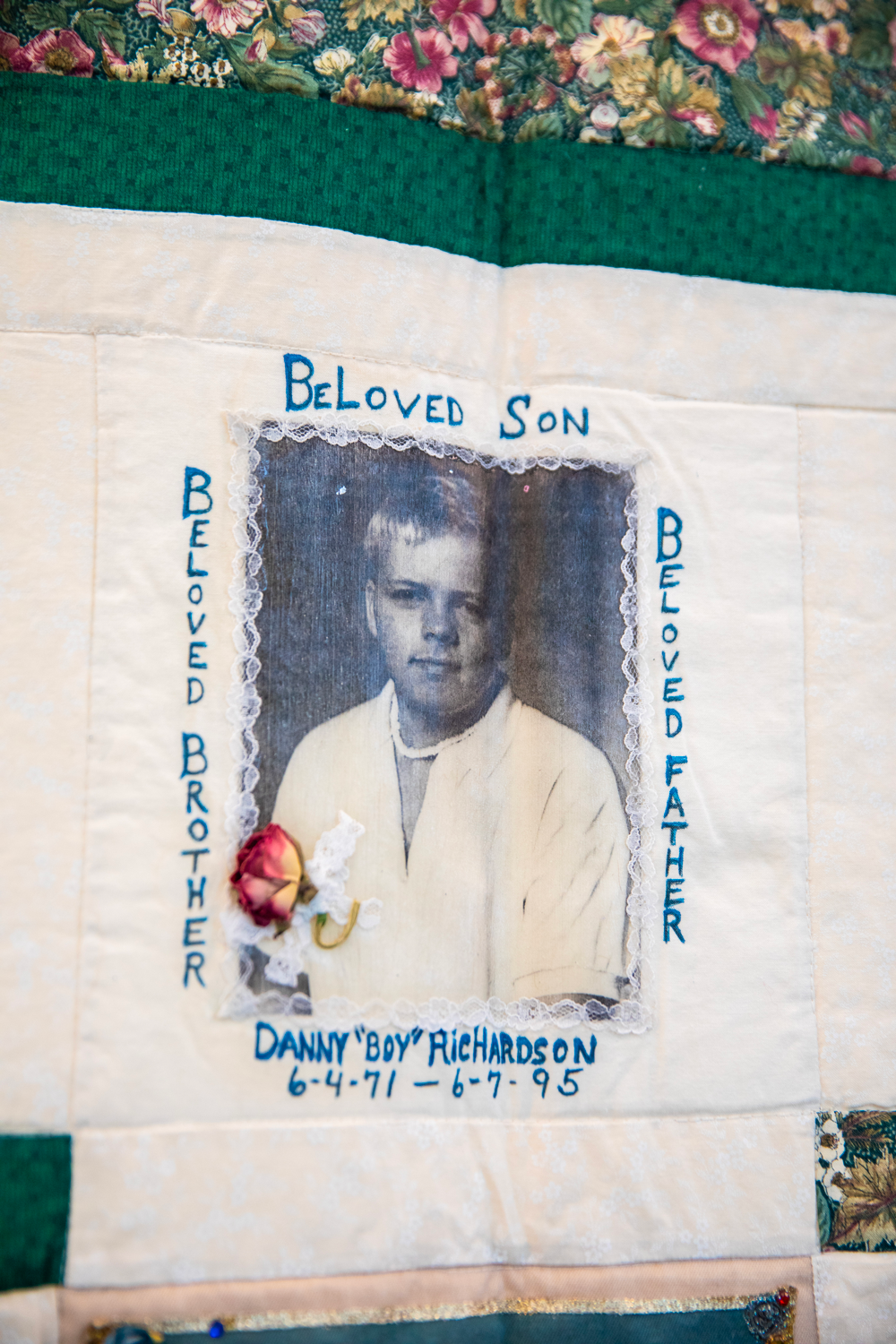 A memorial quilt square with a black-and-white photo of a young boy, labeled 'Beloved Son,' 'Beloved Brother,' and 'Beloved Father.' The name "Danny 'Boy' Richardson" and birth and death dates, June 4, 1971 to June 7, 1995, are embroidered around the