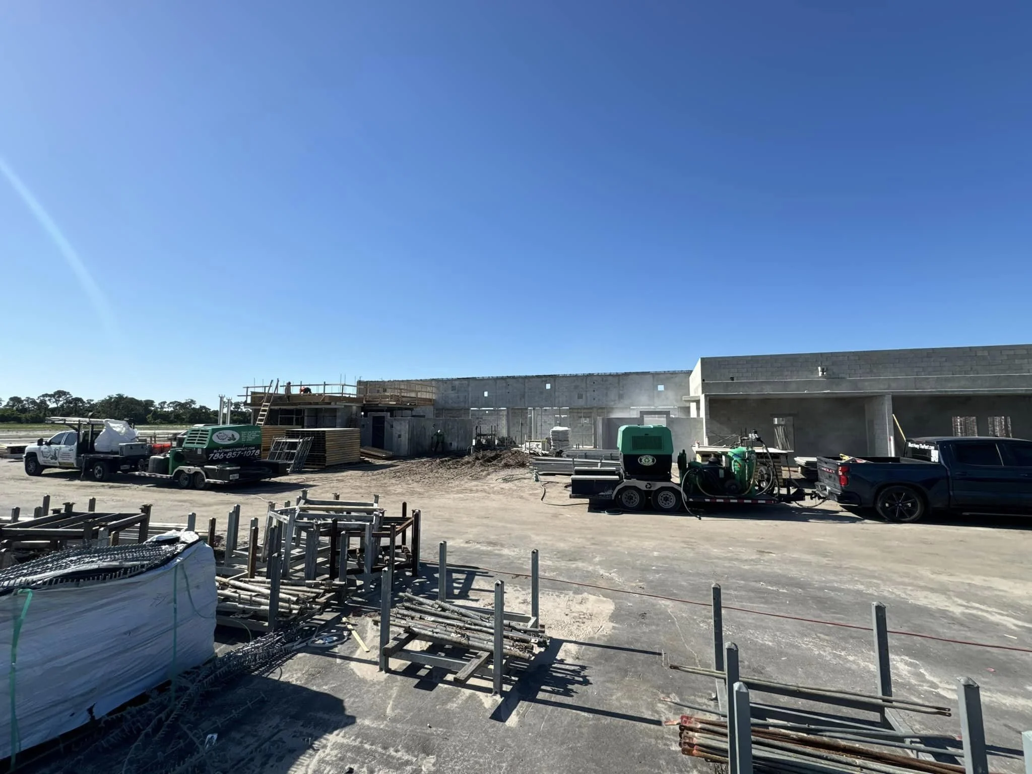 Construction site with trucks and building framework under clear blue sky.