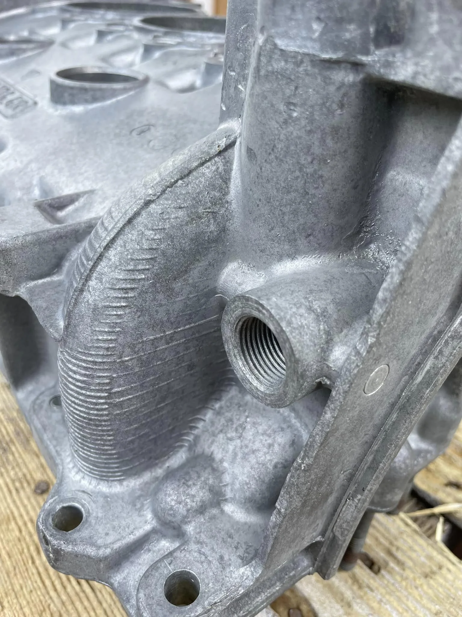 Close-up of a metallic engine block with threaded hole and cooling fins.
