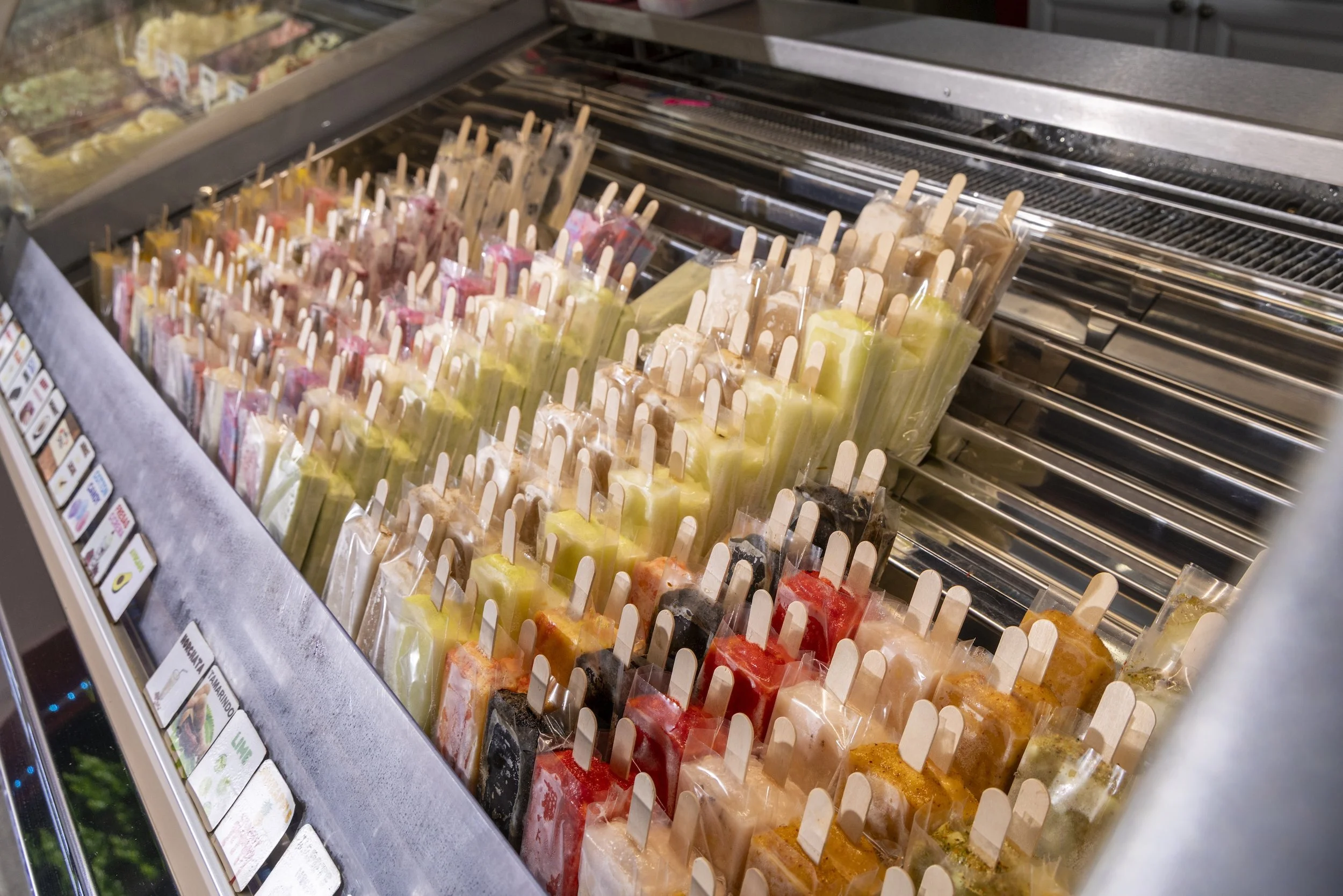 Brightly colored paleta pops sit in a cooler.