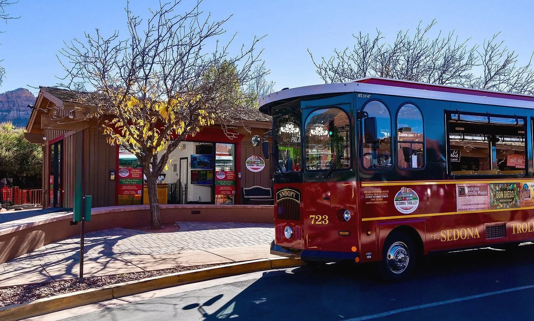 A red and green trolley sits in front of the tour ticket office.