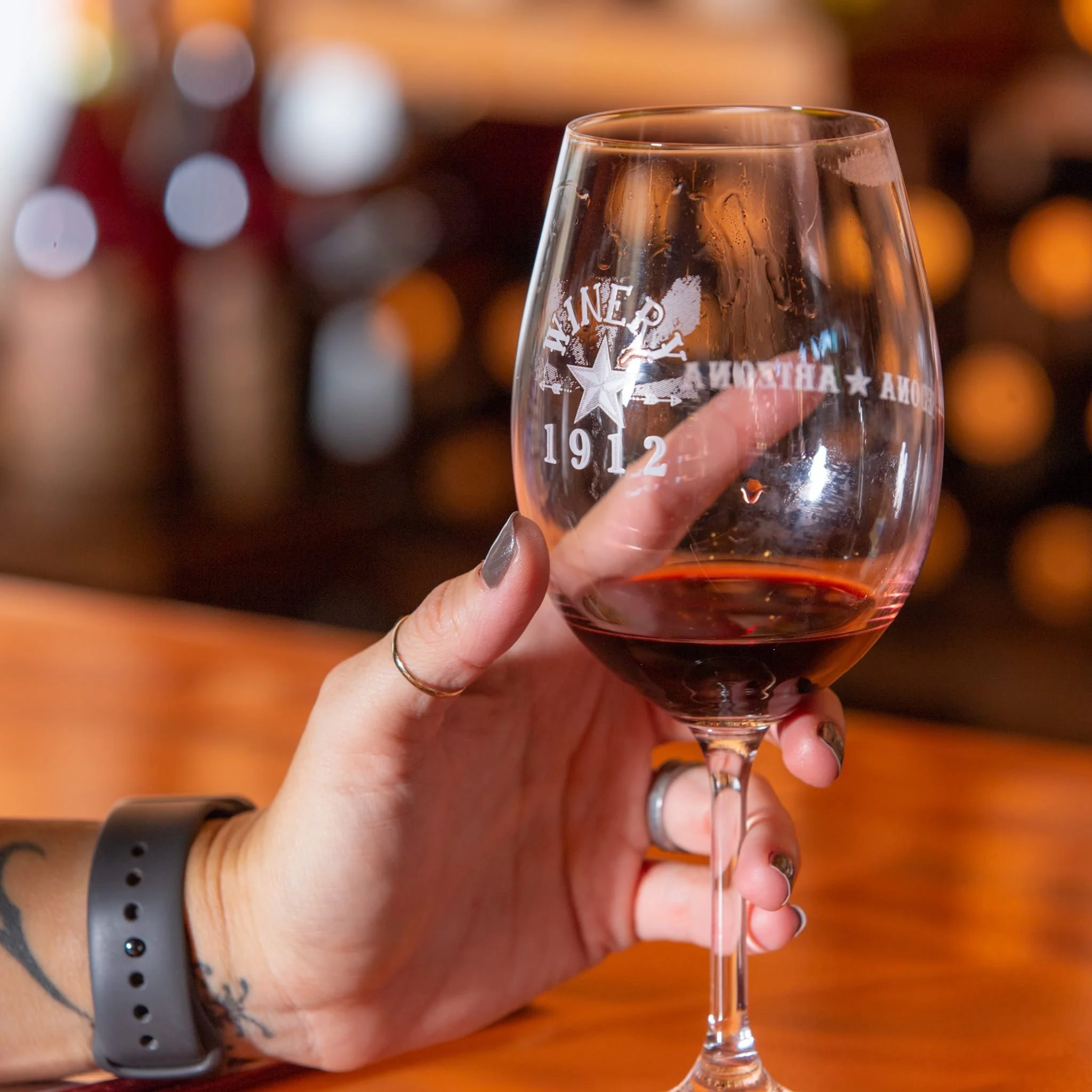 A woman holds a glass of red wine.