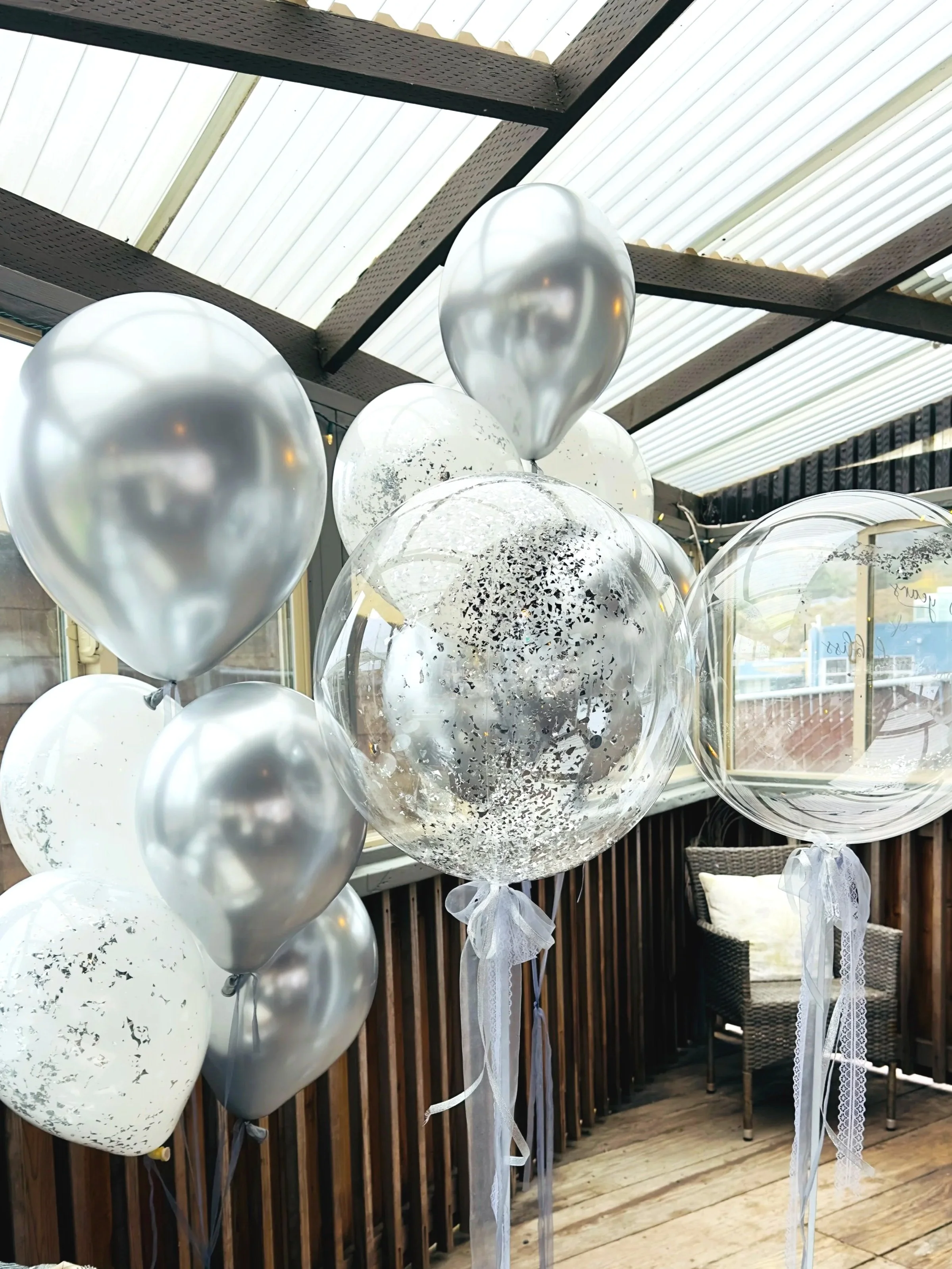 Elegant silver and white helium balloons with confetti, perfect for a stylish birthday celebration in Pacifica.