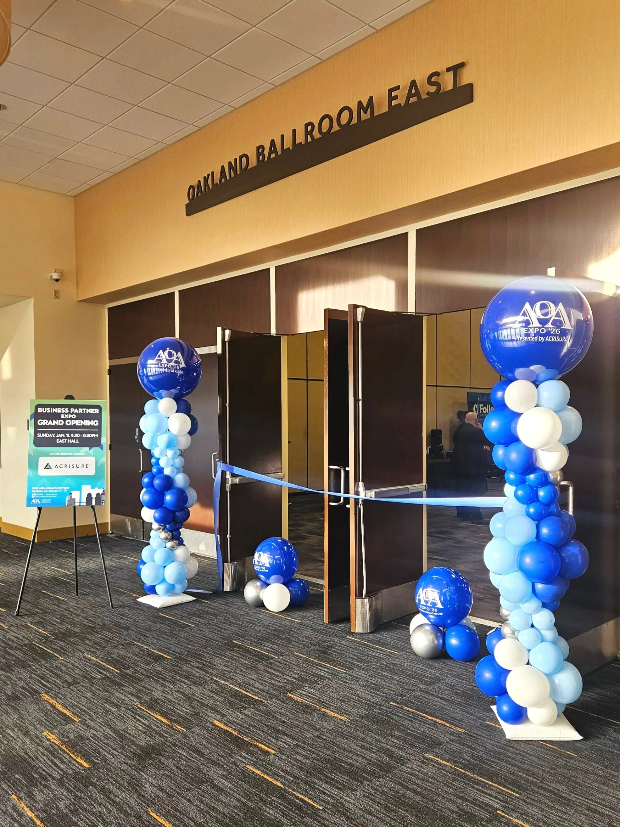 Large-scale annual corporate event installation at Marriott Conference Center in Oakland. Custom balloon decor designed for company-wide celebration, featuring elegant color palette, structured garland installation, and professional event styling.