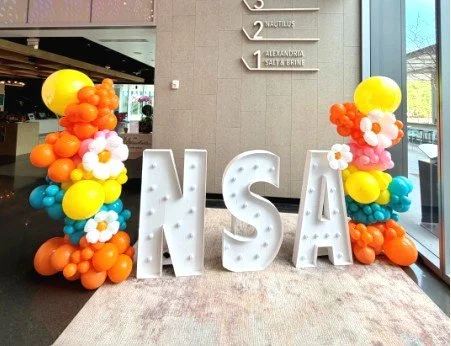 Colorful 80s-themed balloon installation with NMSA marquee letters for a corporate event.