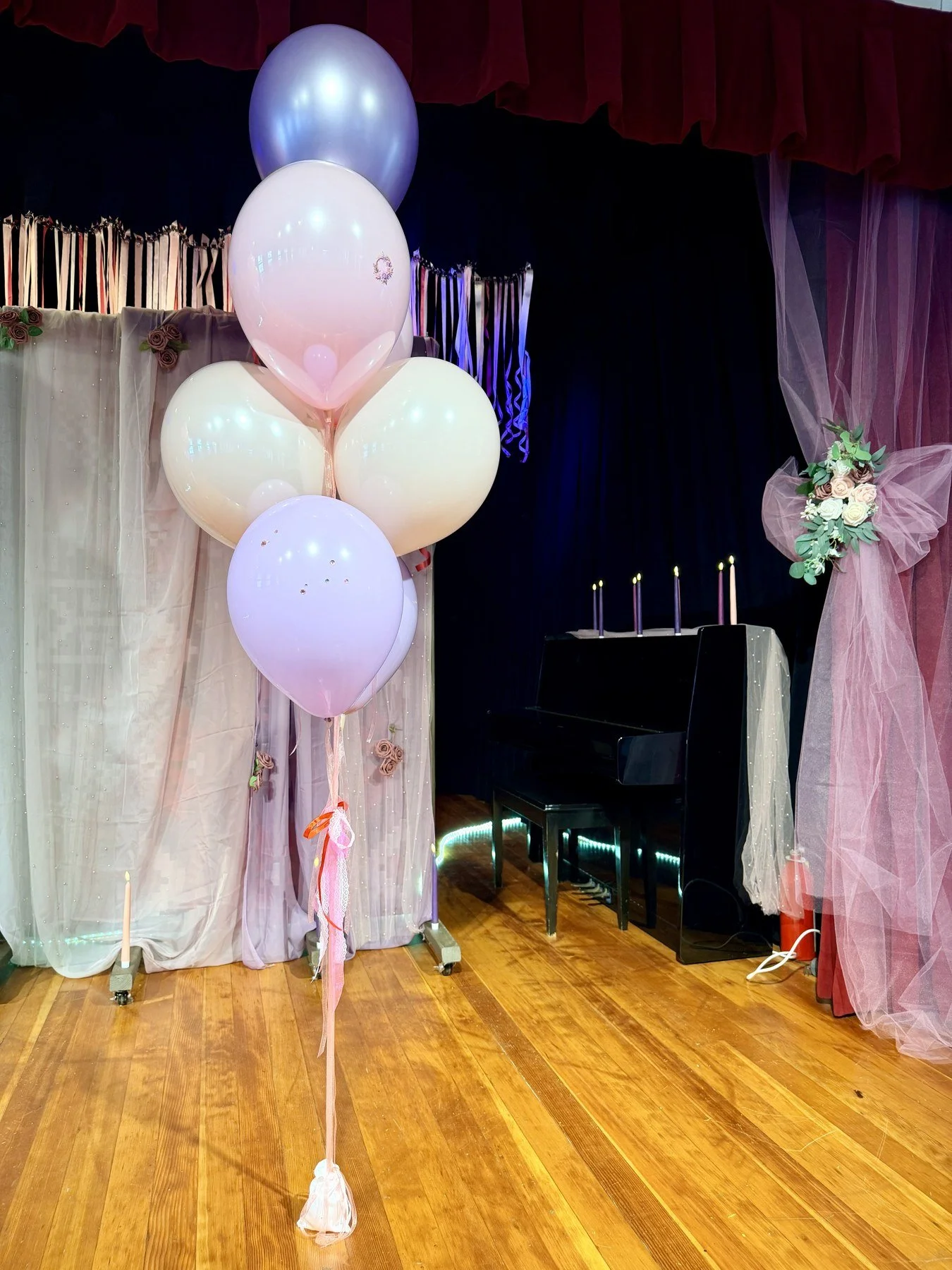 Pastel helium balloon bouquets framing a school graduation stage in San Francisco.