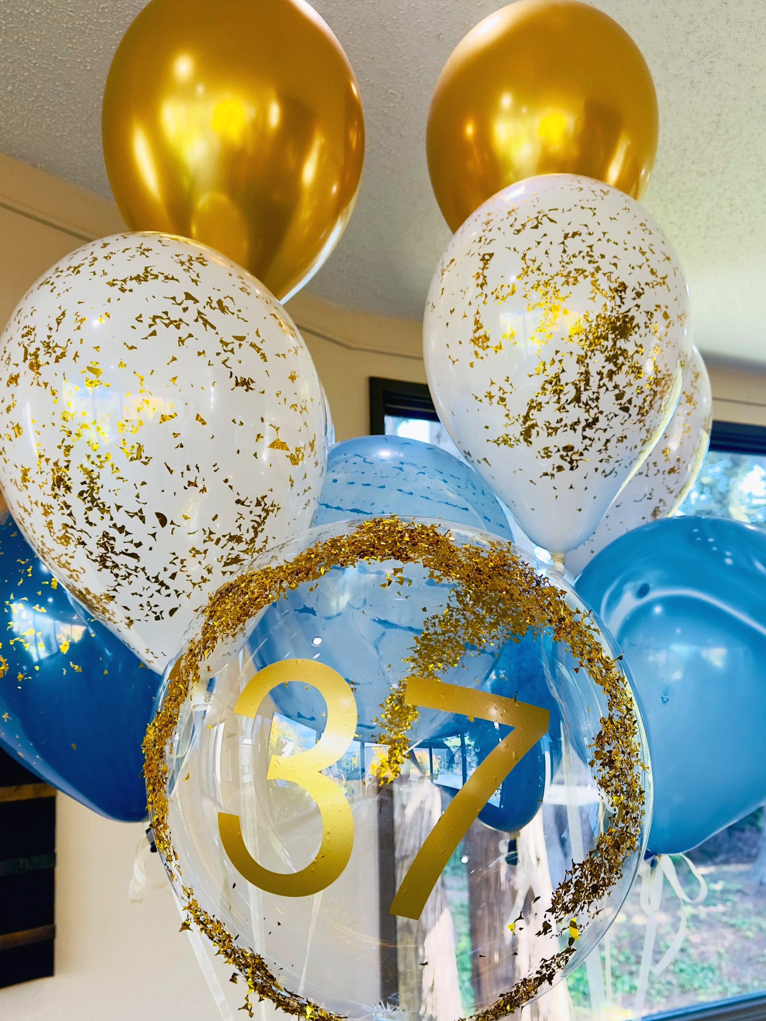 Luxury balloon bouquet with gold confetti and blue helium balloons for 37th birthday party