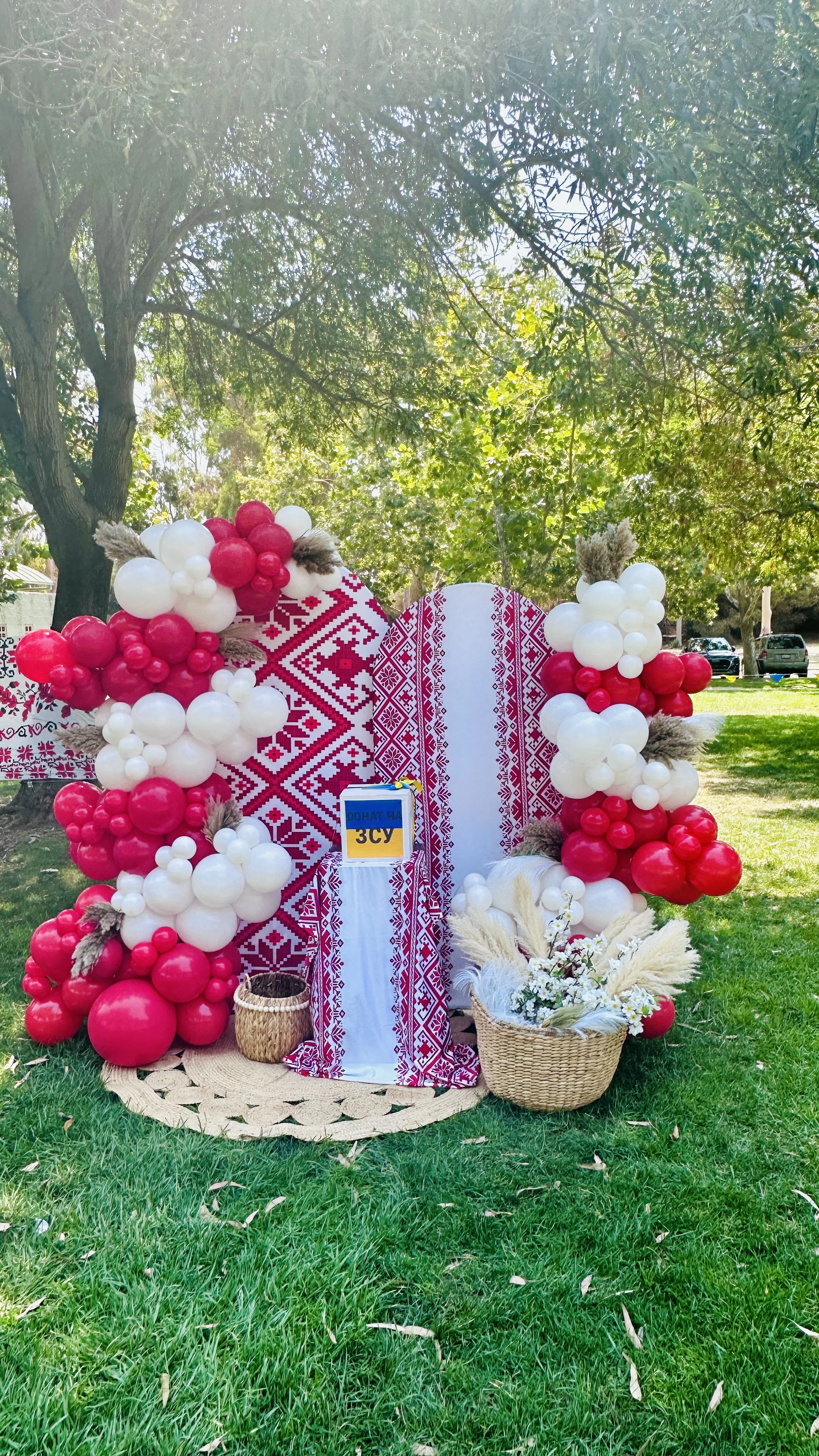 Ukrainian embroidery-inspired backdrop with red and white balloons, wheat and flowers at a Sunnyvale picnic.