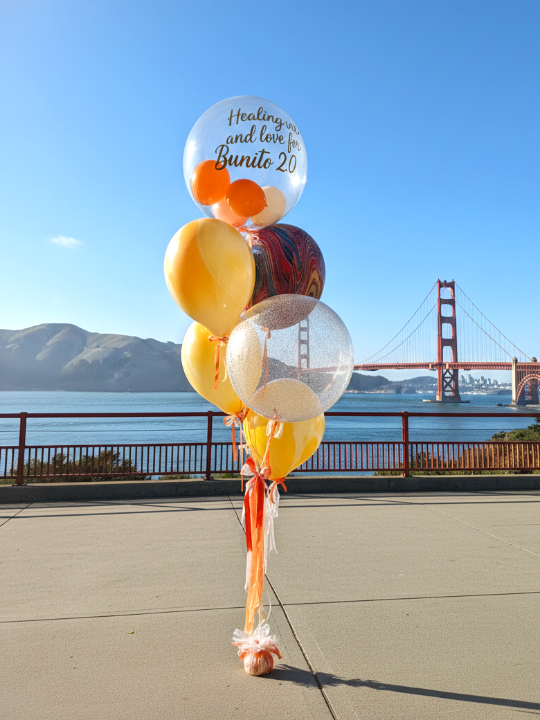 Elegant helium balloon bouquet in orange and gold tones with transparent bobo balloons and custom text for a birthday celebration in the Bay Area.  Title (заголовок): Birthday Helium Balloons | Custom Balloon Bouquet | Bay Area  Tags (теги): birthday
