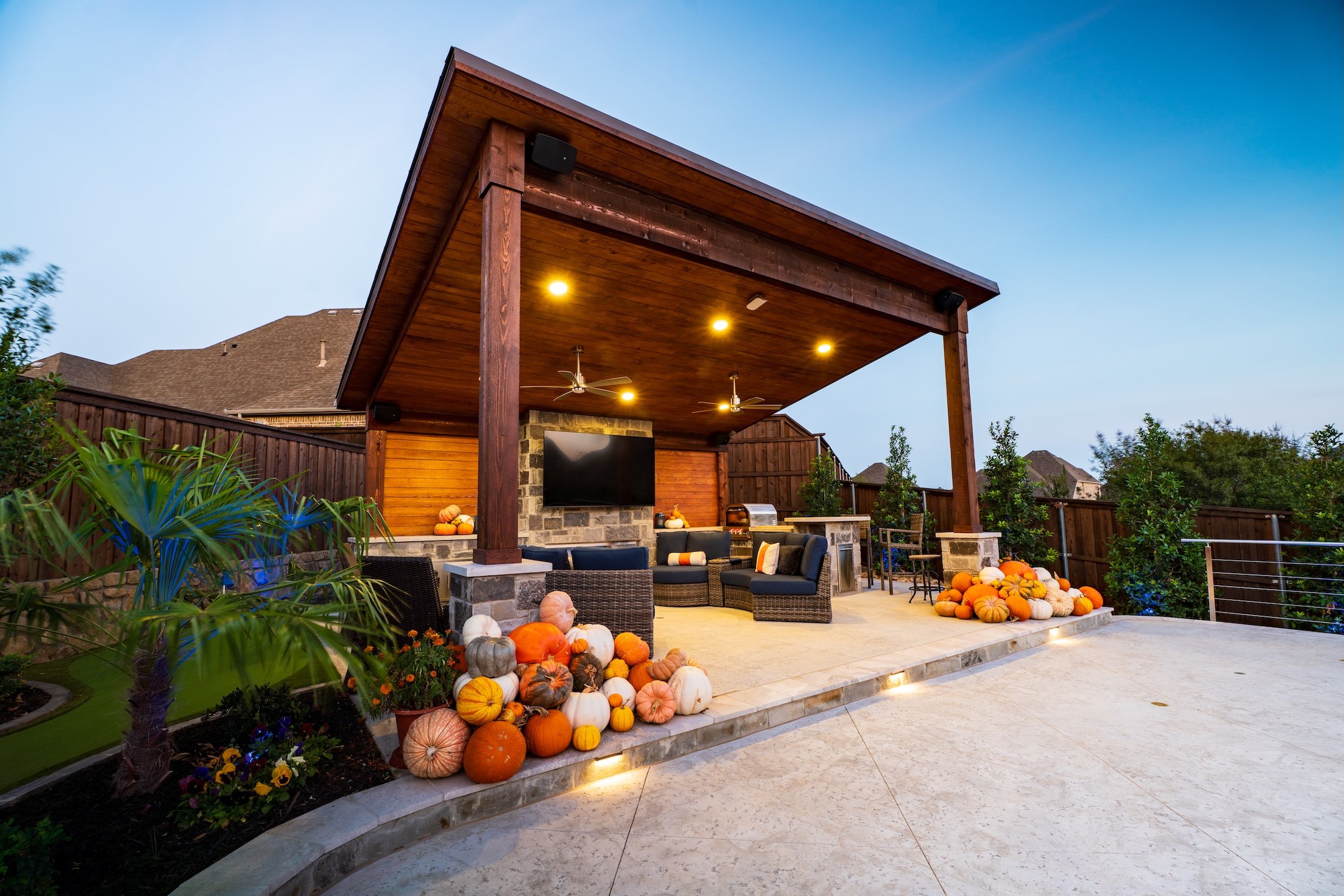 Outdoor patio with a wooden roof, seating area, TV, and fall-themed pumpkin decorations.