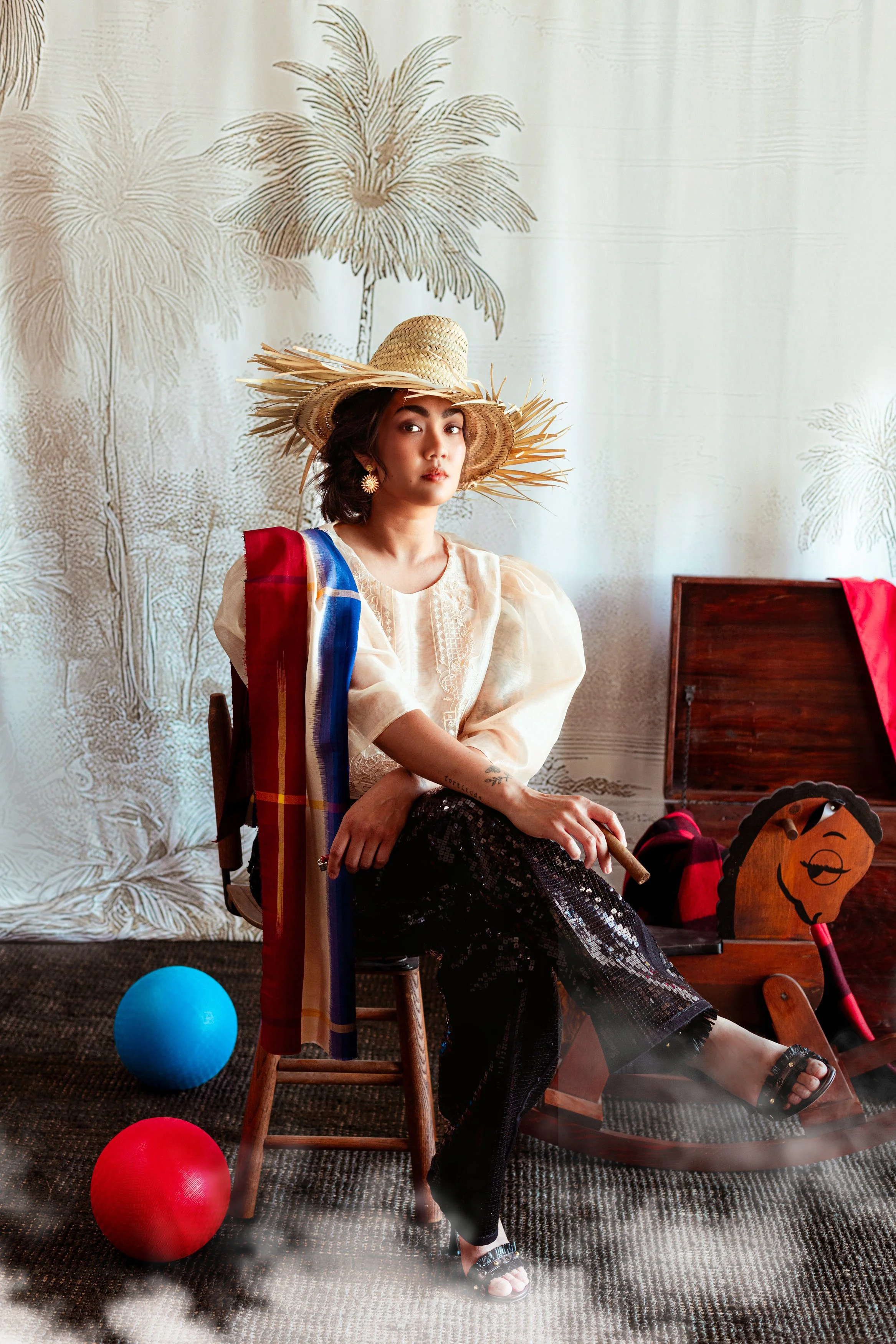 Woman wearing traditional Filipino terno blouse with sequined pants, a multicolored scarf, and a straw hat poses for a photograph