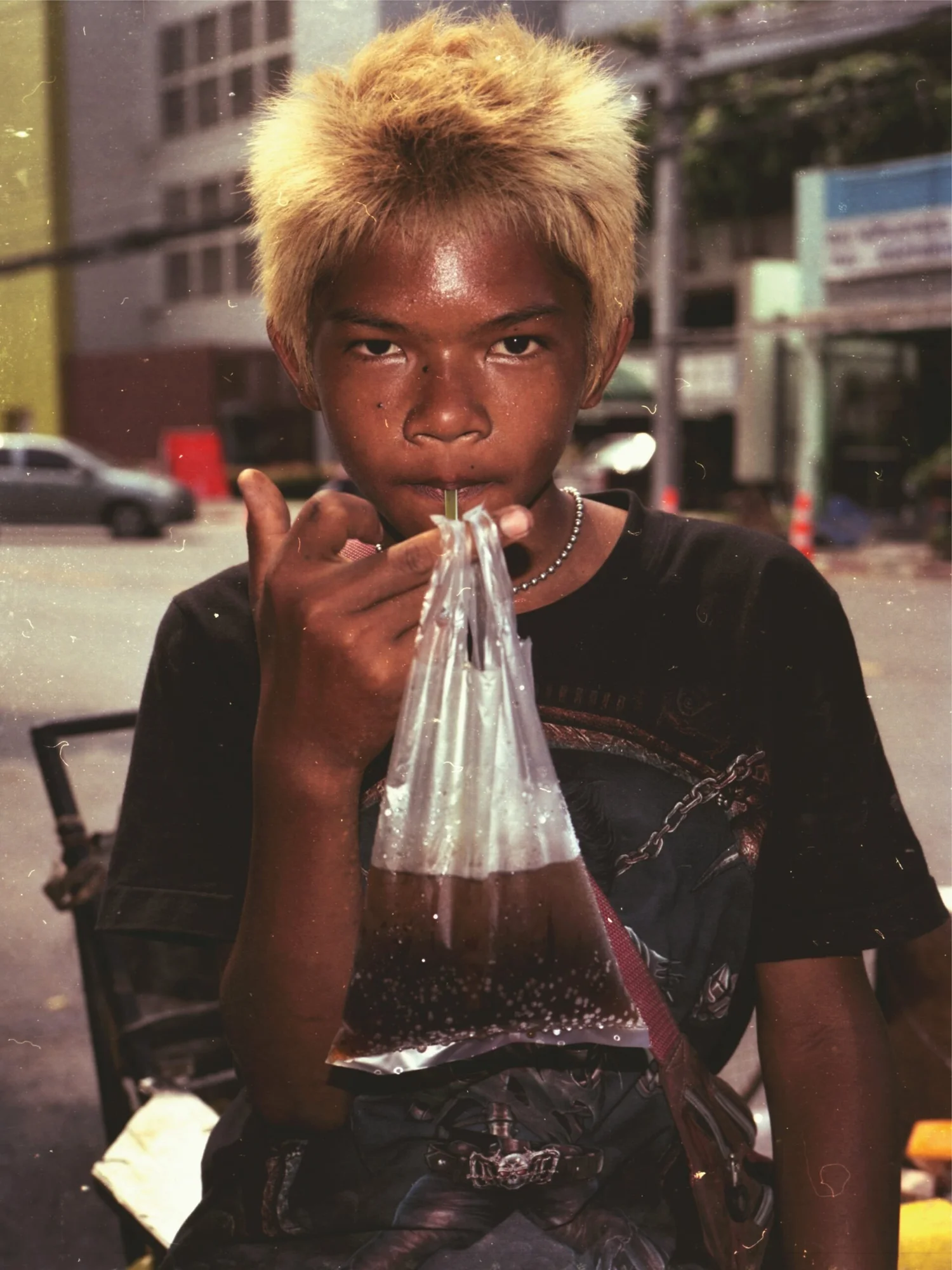 A boy sipping soda from a plastic bag