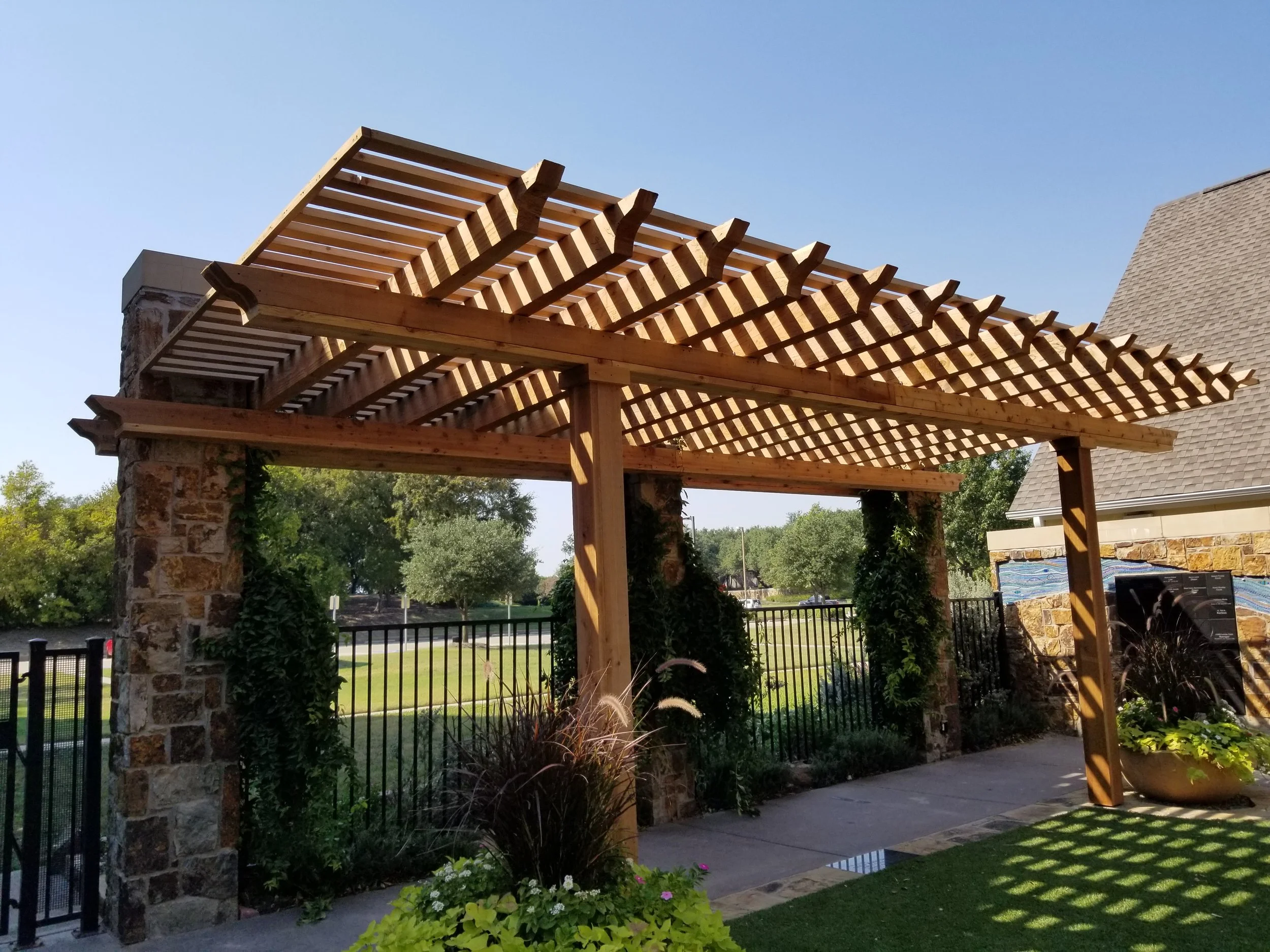 Wooden pergola with stone pillars and a decorative landscape on the wall in a garden.
