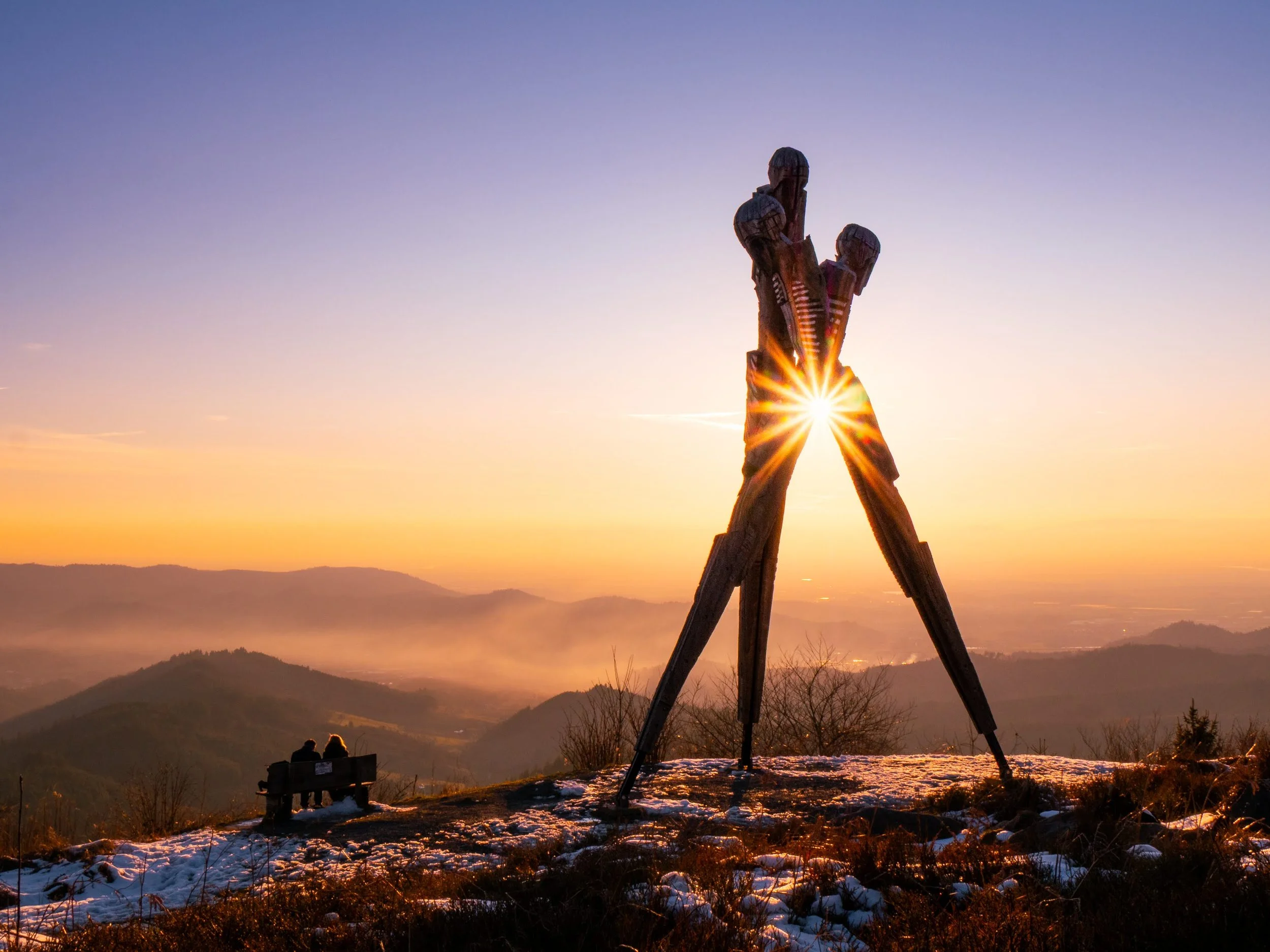 Das Lothardenkmal im Schwarzwald wird von einem goldenen Sonnenstern dekoriert, im Hintergrund Nebelschwaden zwischen den Bergen