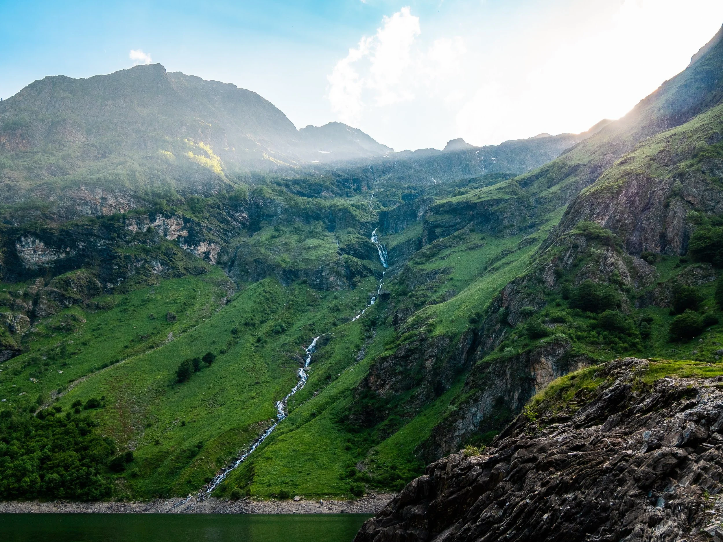 Lac d'Oo in den Pyrenäen: Ein letzter Sonnenstrahl fällt zwischen den Bergen auf die Landschaft