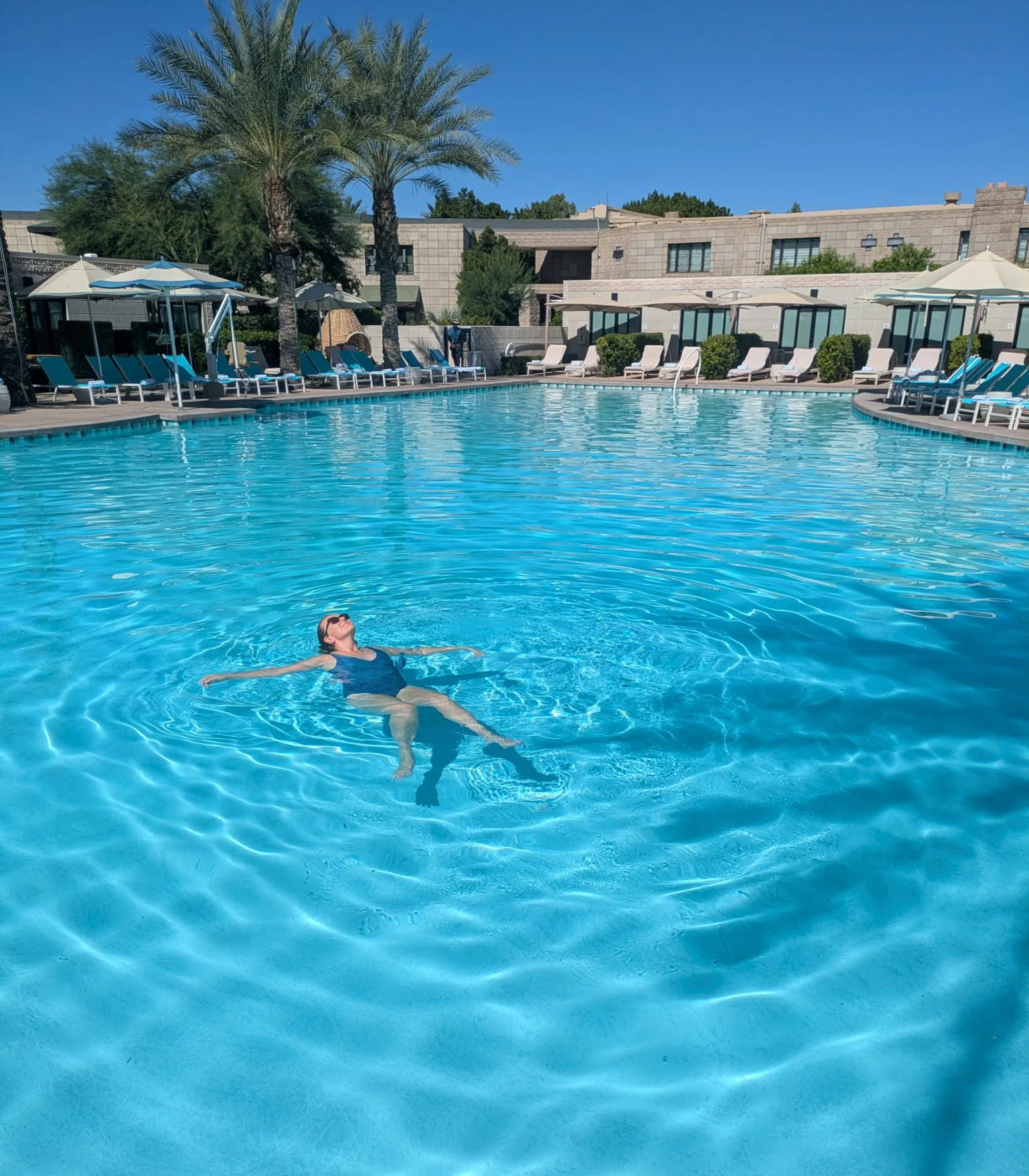 floating in a pool with the shadow of a palm tree