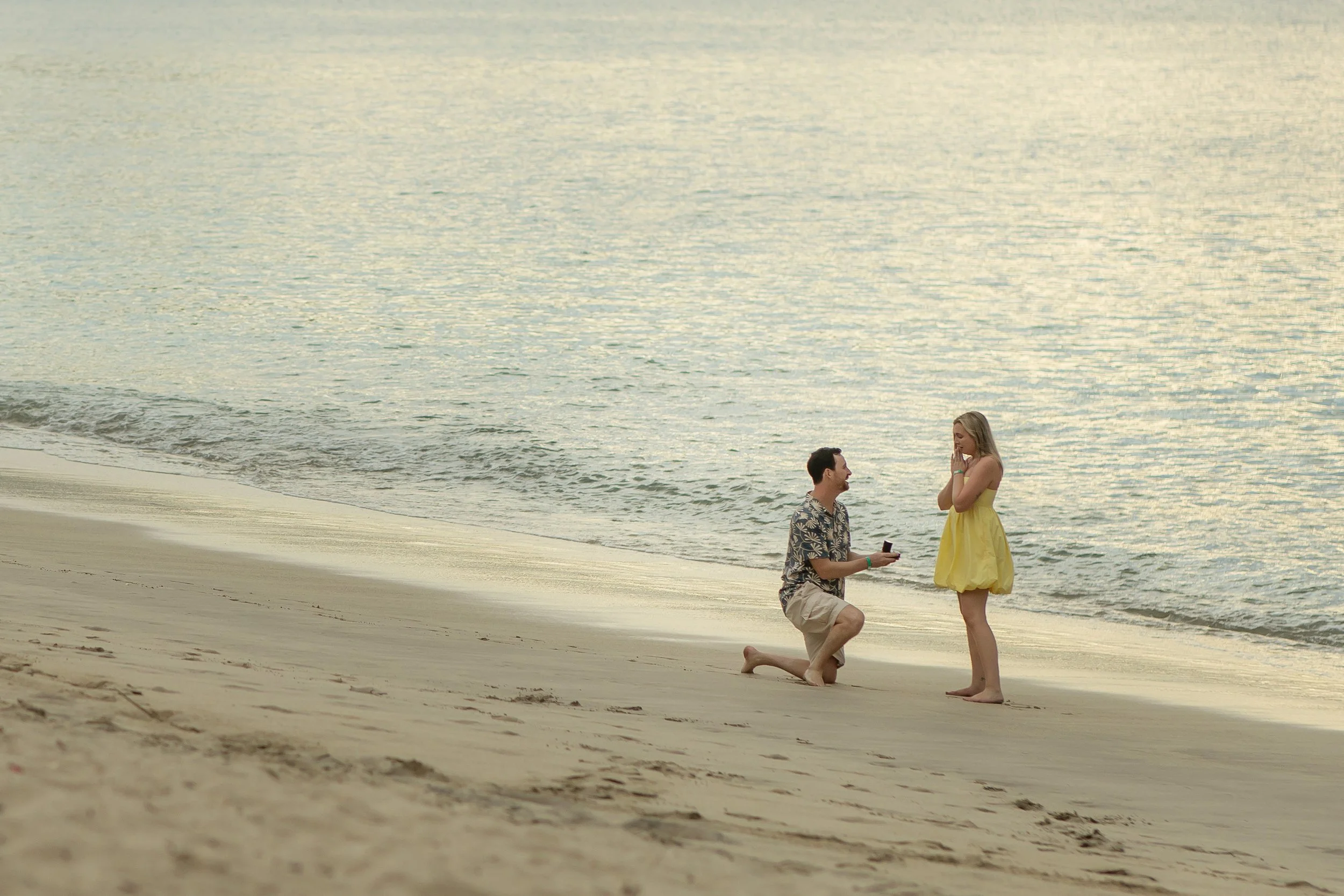 Connor proposing marriage to Kathleen on the beach in Costa Rica during sunset, with the ocean in the background.