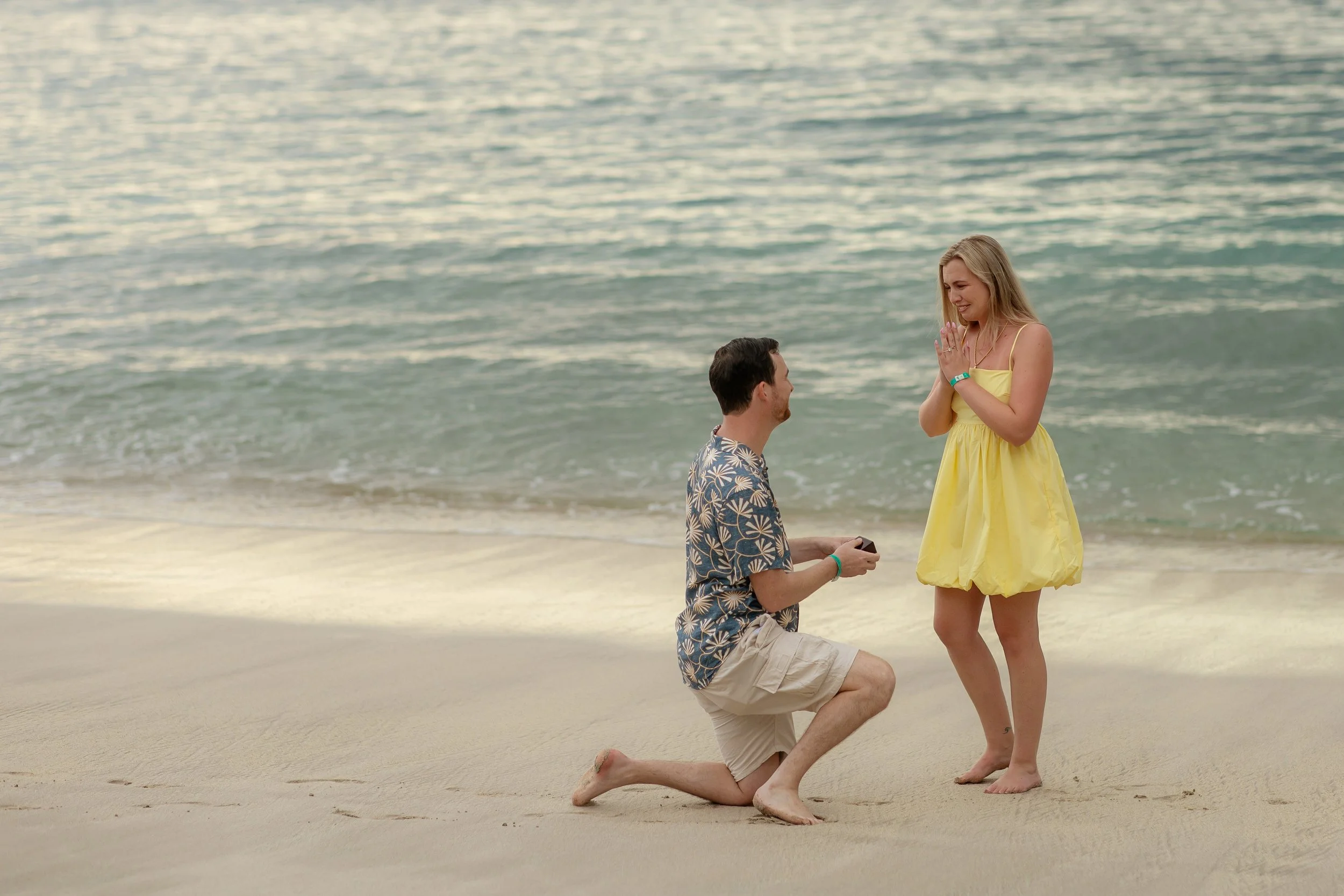 Connor proposing marriage to Kathleen on the beach in Costa Rica during sunset, with the ocean in the background.