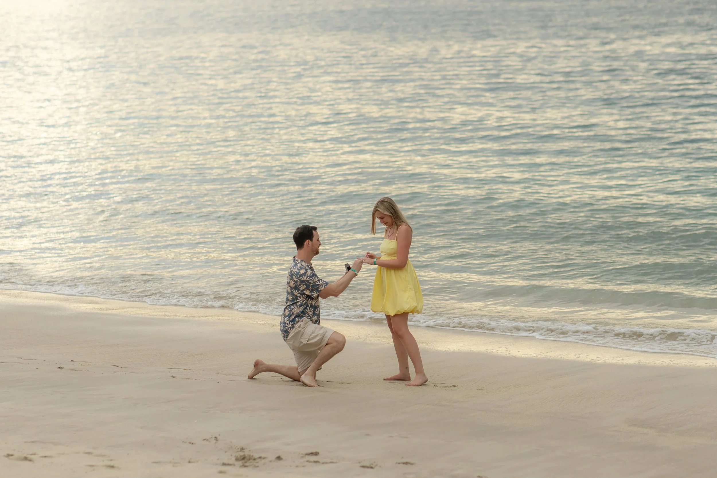 Connor proposing marriage to Kathleen on the beach in Costa Rica during sunset, with the ocean in the background.