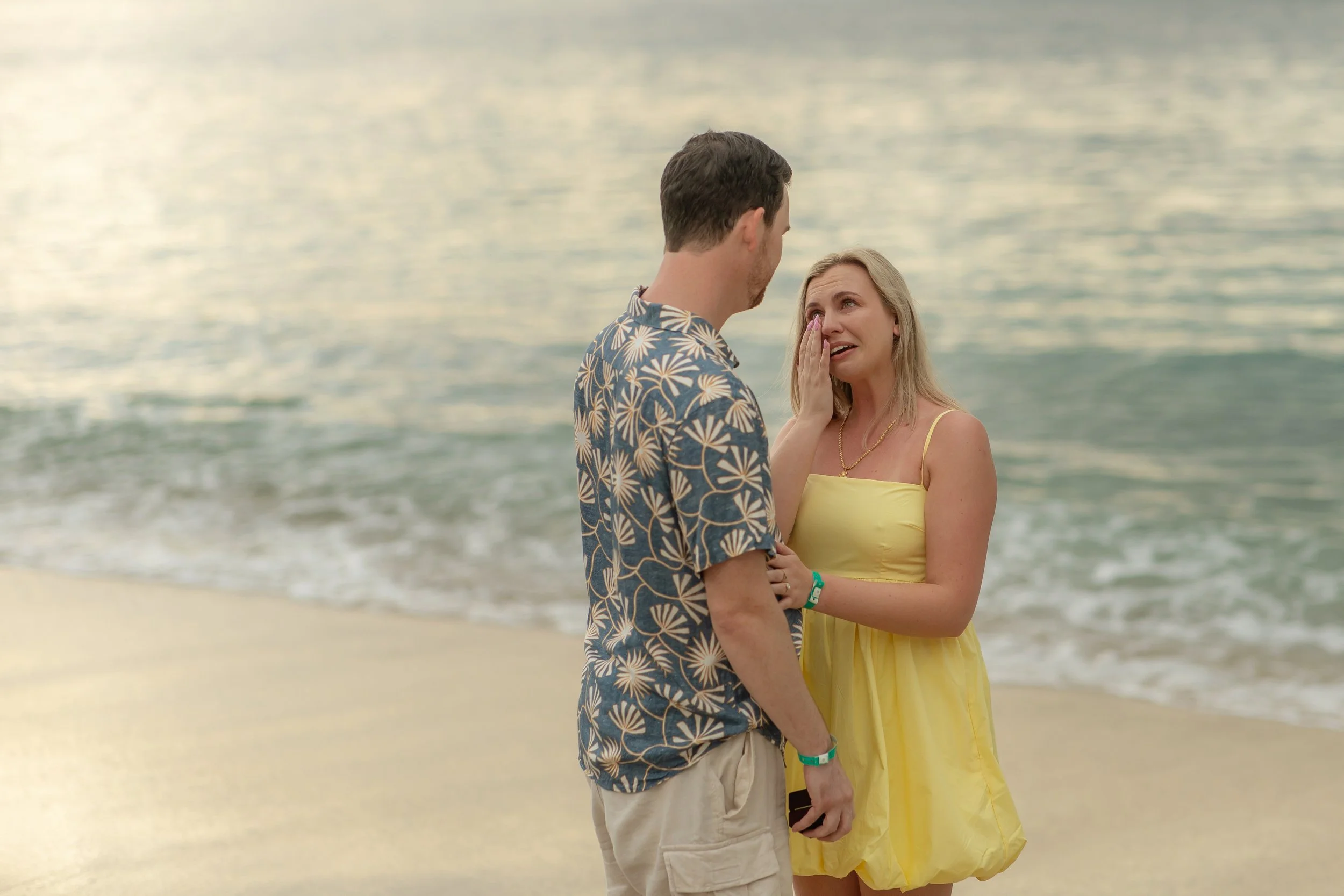 Connor proposing marriage to Kathleen on the beach in Costa Rica during sunset, with the ocean in the background.
