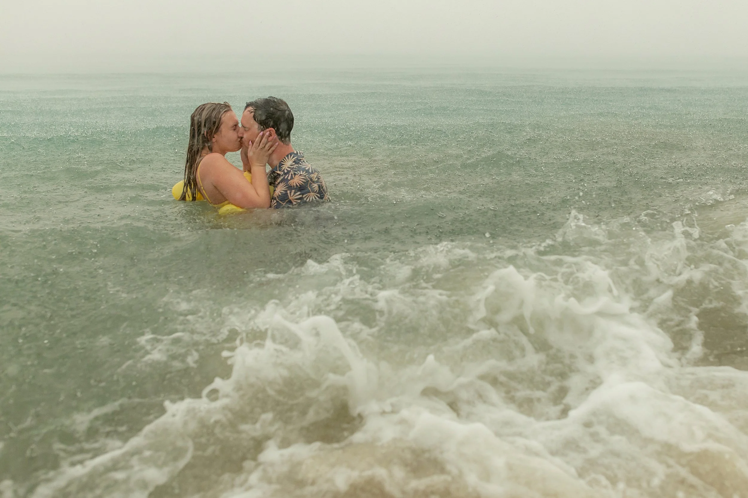 A couple kissing while standing in the ocean.