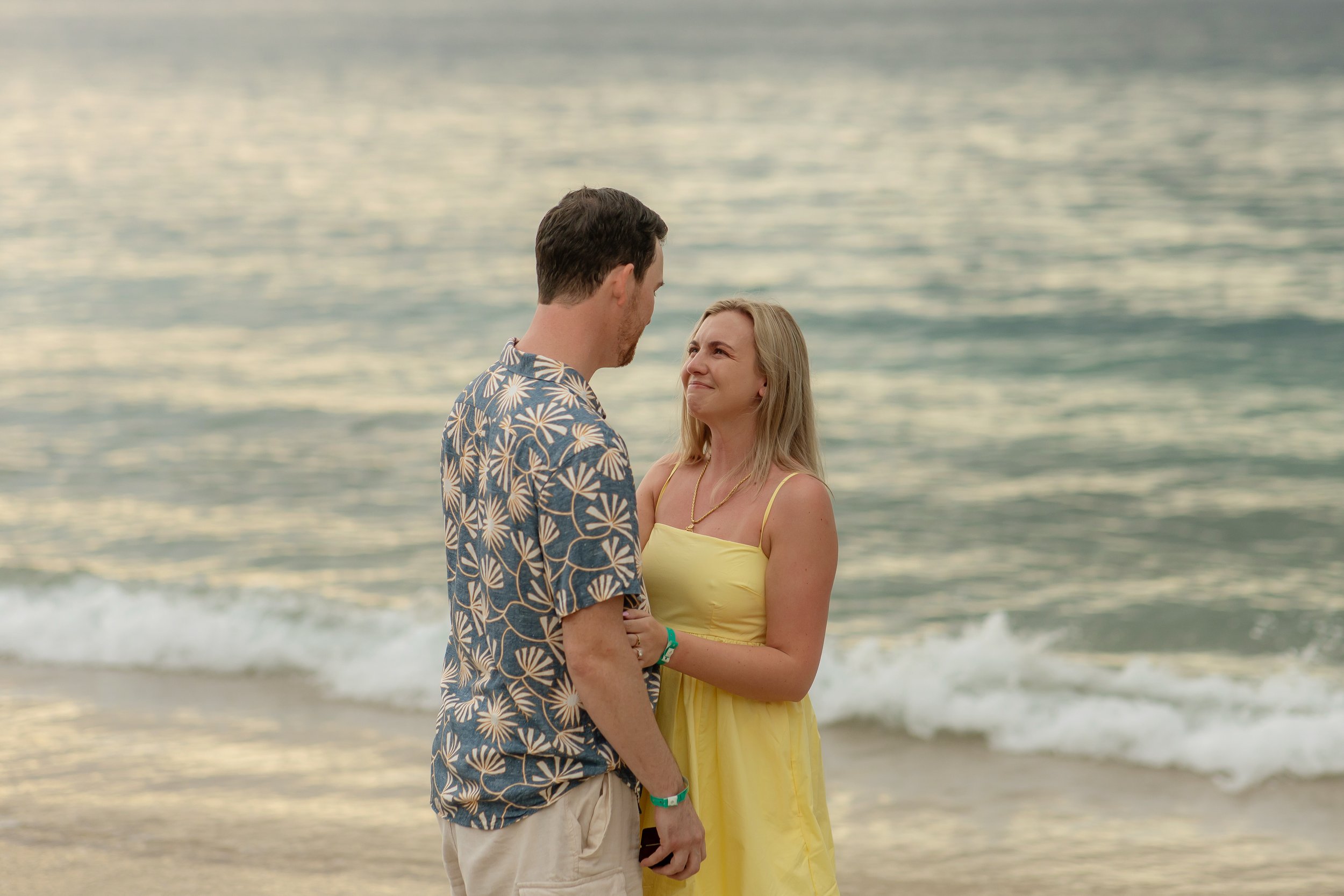 Connor proposing marriage to Kathleen on the beach in Costa Rica during sunset, with the ocean in the background.