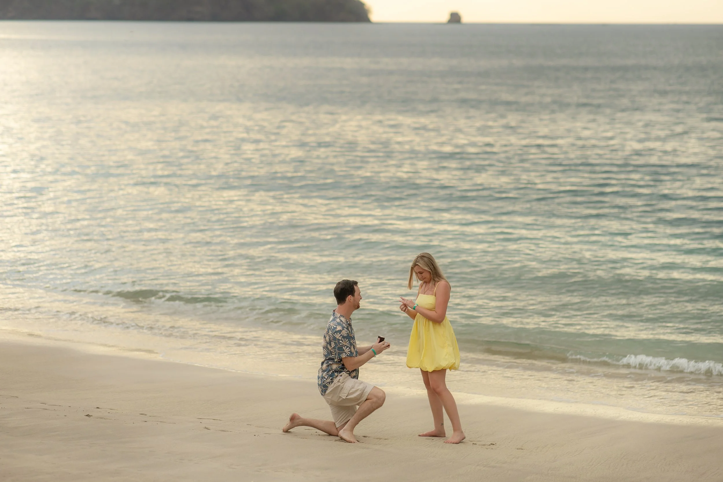 Connor proposing marriage to Kathleen on the beach in Costa Rica during sunset, with the ocean in the background.
