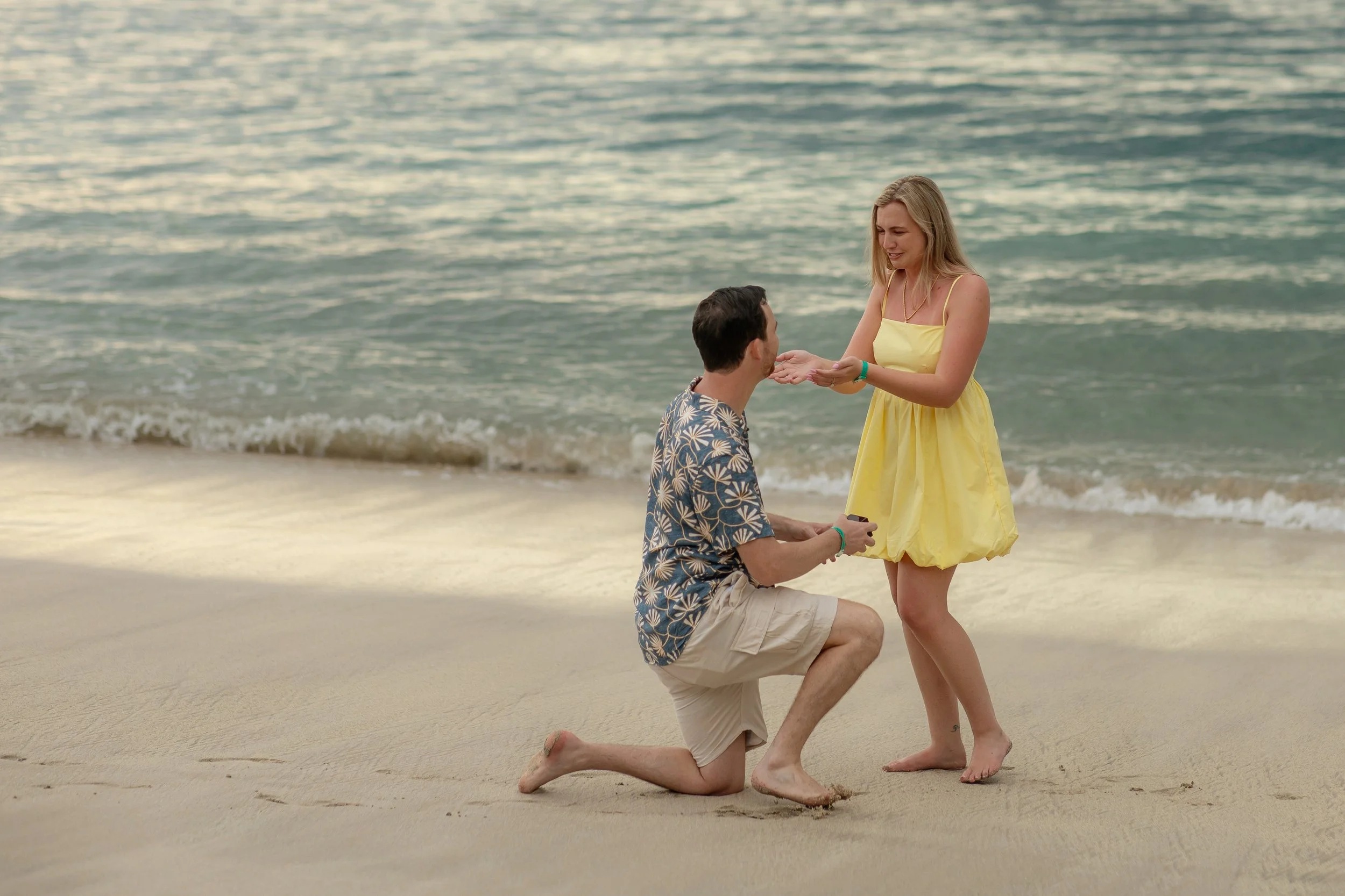Connor proposing marriage to Kathleen on the beach in Costa Rica during sunset, with the ocean in the background.