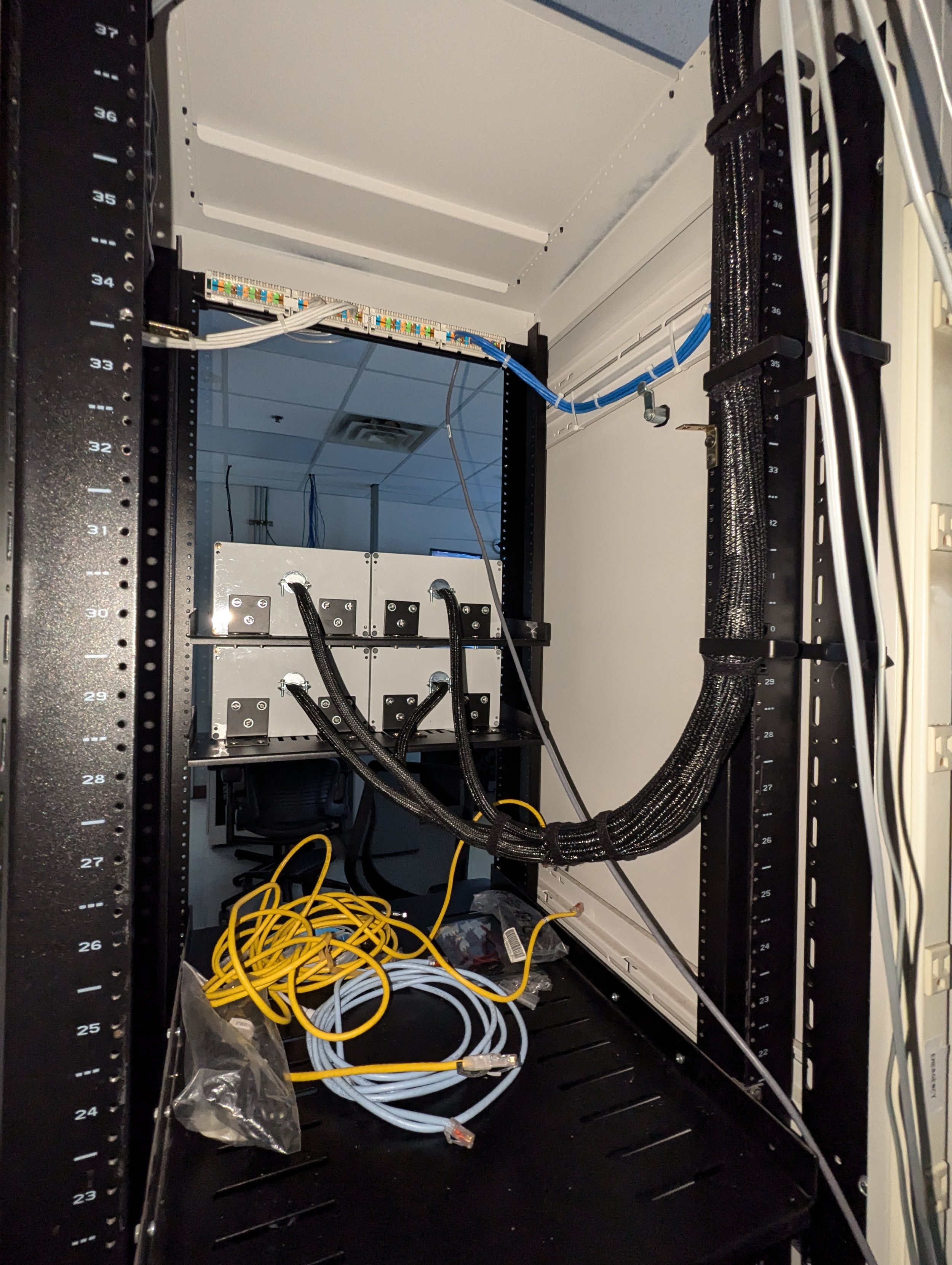 Inside a server or network equipment rack with cables, switches, and hardware components installed. Custom Controls BOX. Toggle. Emergency. Rack Mount. Indicator LED. LOCKDOWN