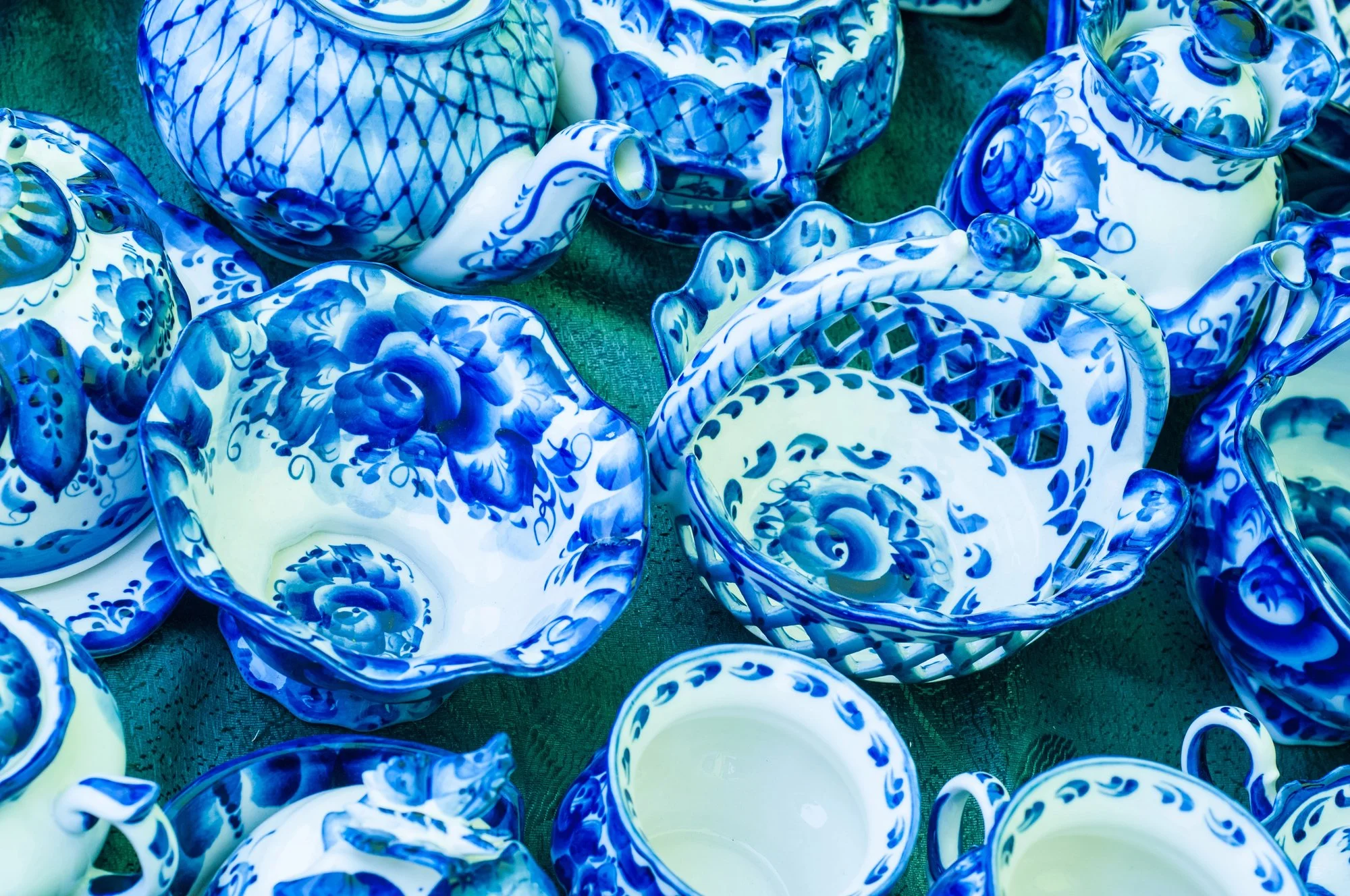 Collection of antique blue and white porcelain teapots, cups, and bowls with floral and geometric patterns.