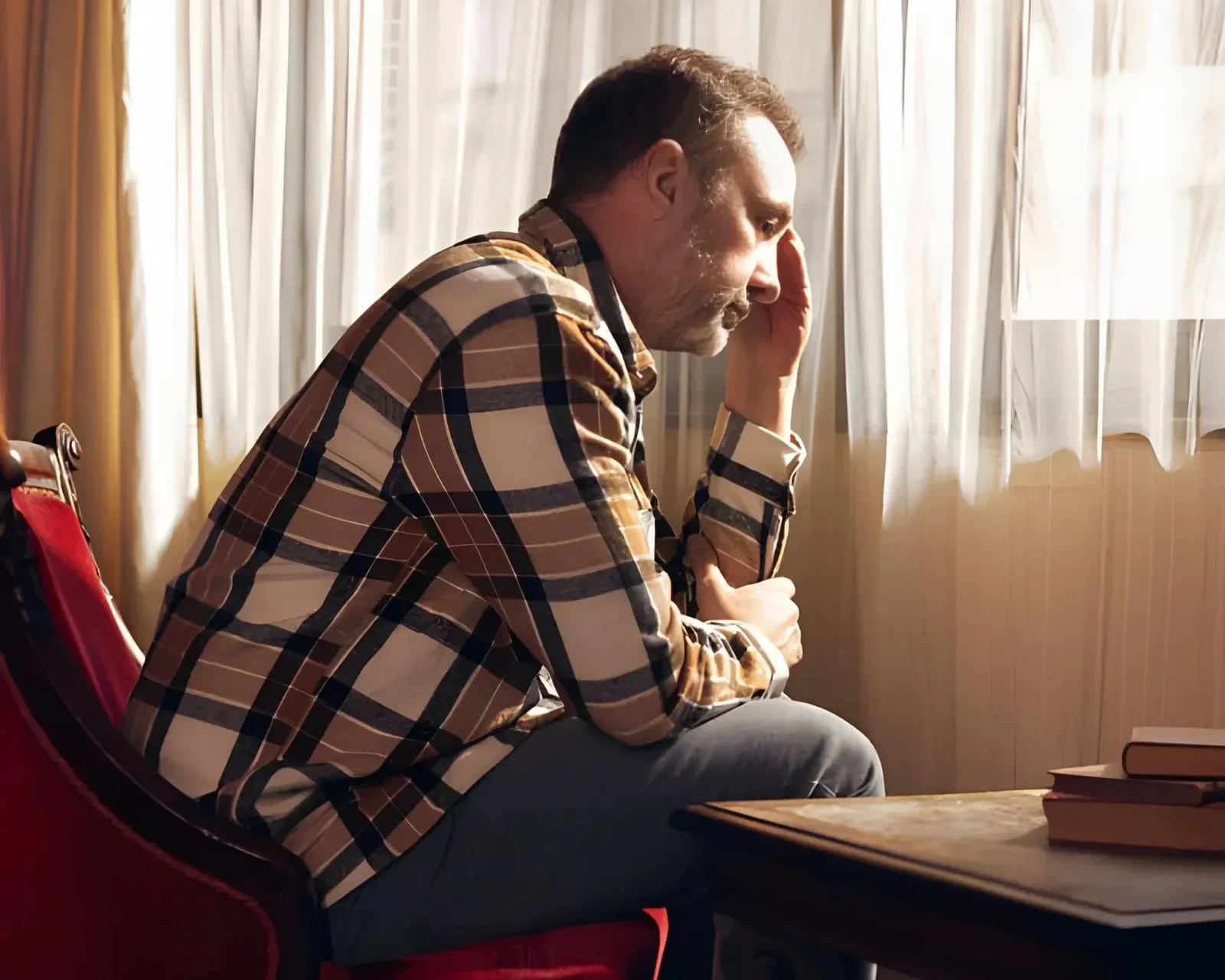 A man sitting facing the window looking stressed
