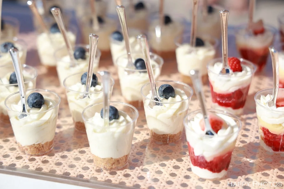 Mini parfait cups topped with blueberries and raspberries on a tray.