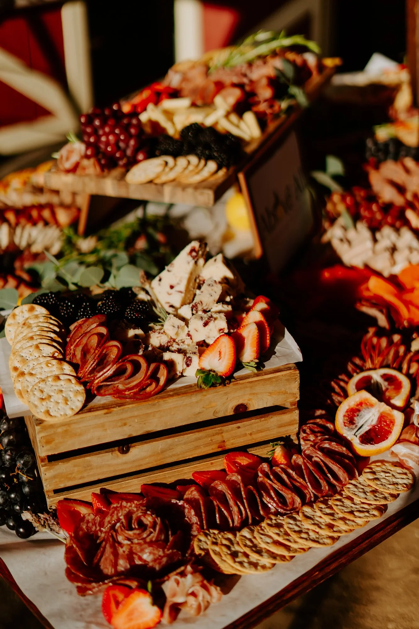 A charcuterie board with various sliced fruits, crackers, cheeses, and meats displayed on a wooden tray.