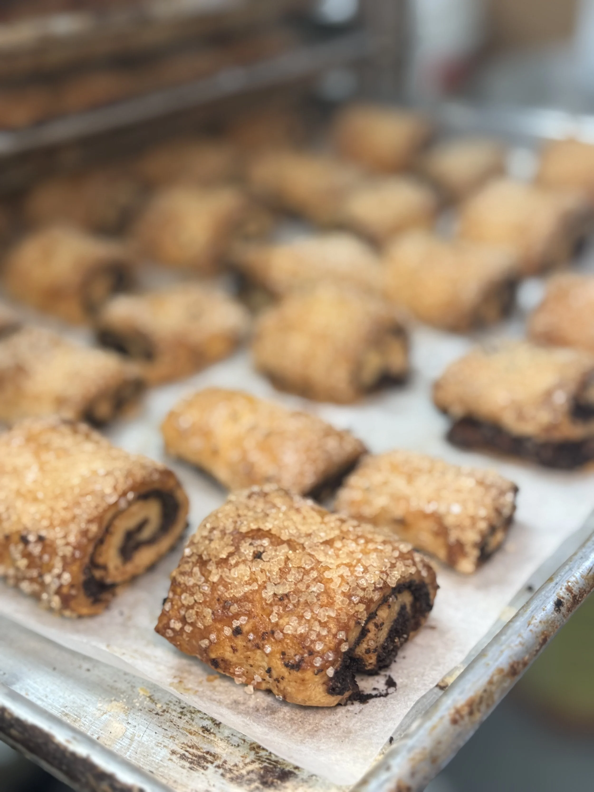 Close-up of cinnamon roll cake bites with sugar crystals on top, cooling on a baking sheet lined with parchment paper.