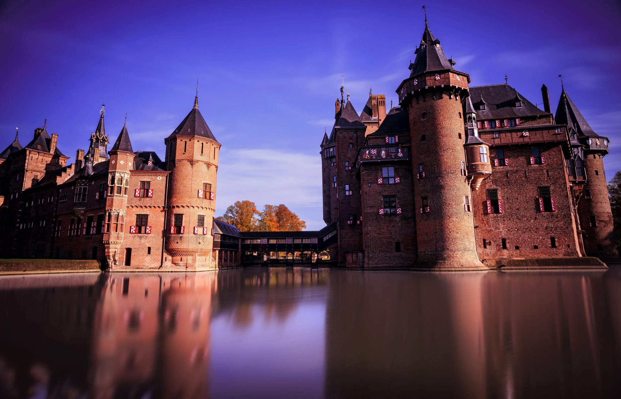 A large medieval castle with multiple towers and a moat surrounding it, under a night sky.