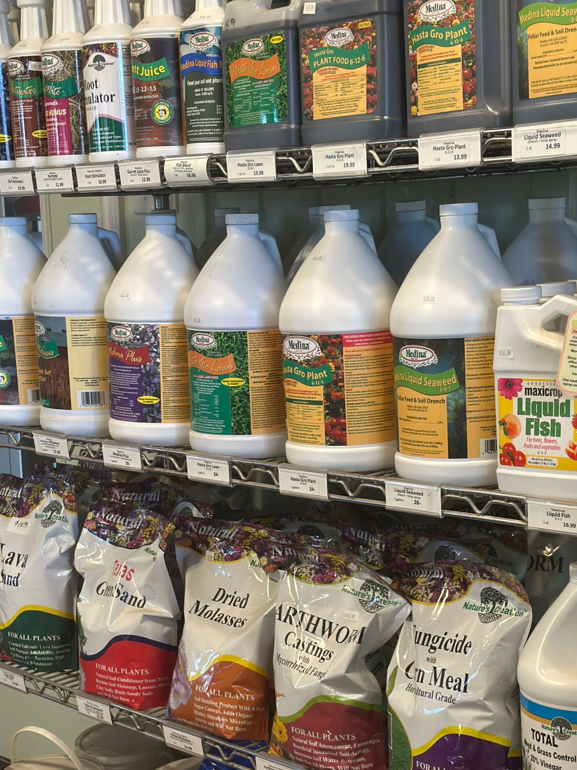 Garden products on store shelves including liquid seaweed, plant food, liquid fish, dried molasses, and castings for all plants.