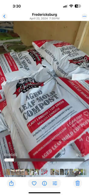 Bags of seasoned, aged leaf mold compost from Geiloo Farms, stacked on a wooden surface.