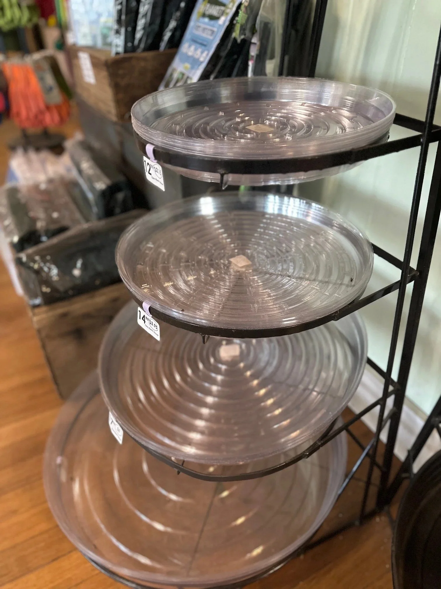 Clear plastic round trays stacked on black metal rack.