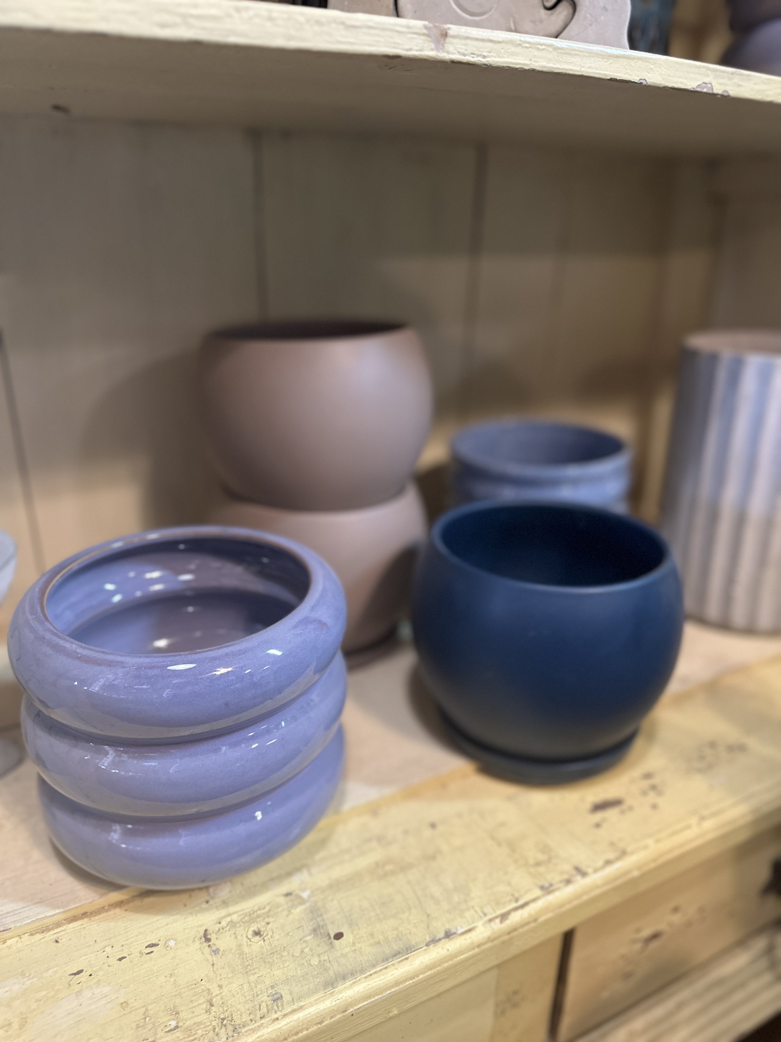 Colorful ceramic pots on wooden shelf in a store.