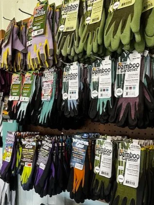 Display of gardening gloves in various colors and sizes hanging on a store rack.
