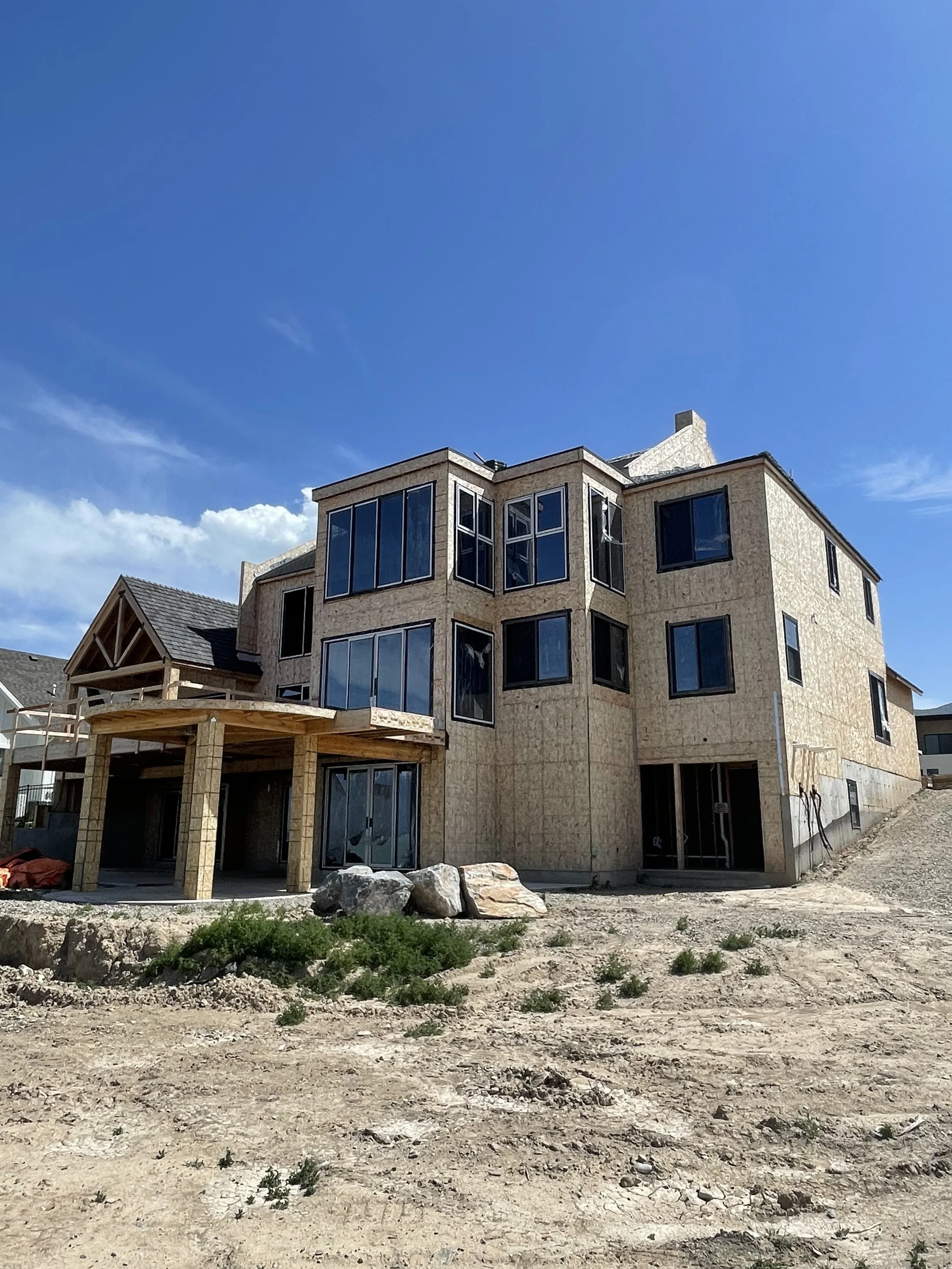 Under construction house with wood framing, large windows, and a clear blue sky