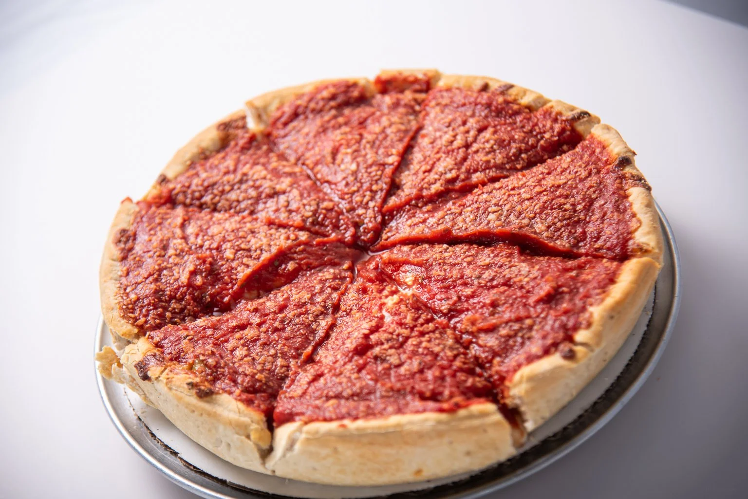 A pepperoni pizza with a thick crust, topped with tomato sauce and cheese, sliced into six pieces.