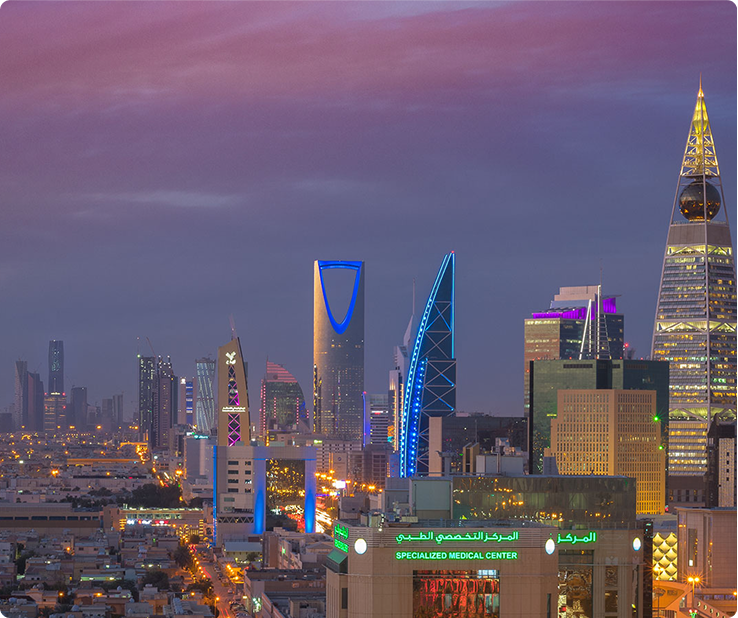 City skyline of Riyadh, Saudi Arabia, at dusk, featuring skyscrapers with colorful neon lights.