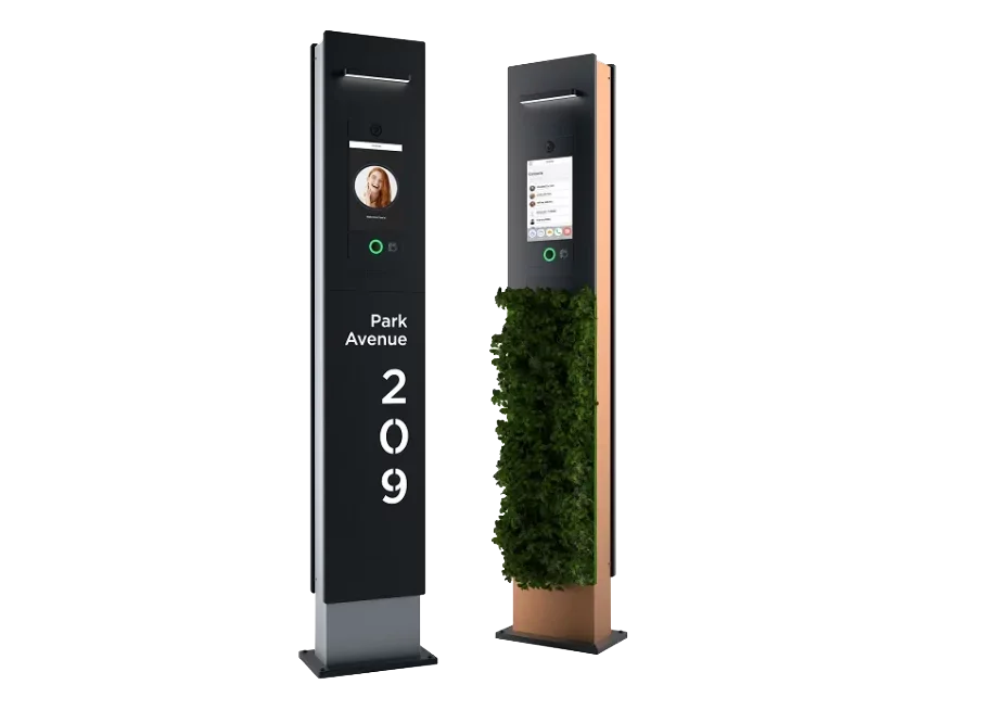 Two modern interactive directory signs for building 209 on Park Avenue, one black with a video screen showing a woman's face, and one copper-colored with a screen displaying messages, and a tall green plant between them.