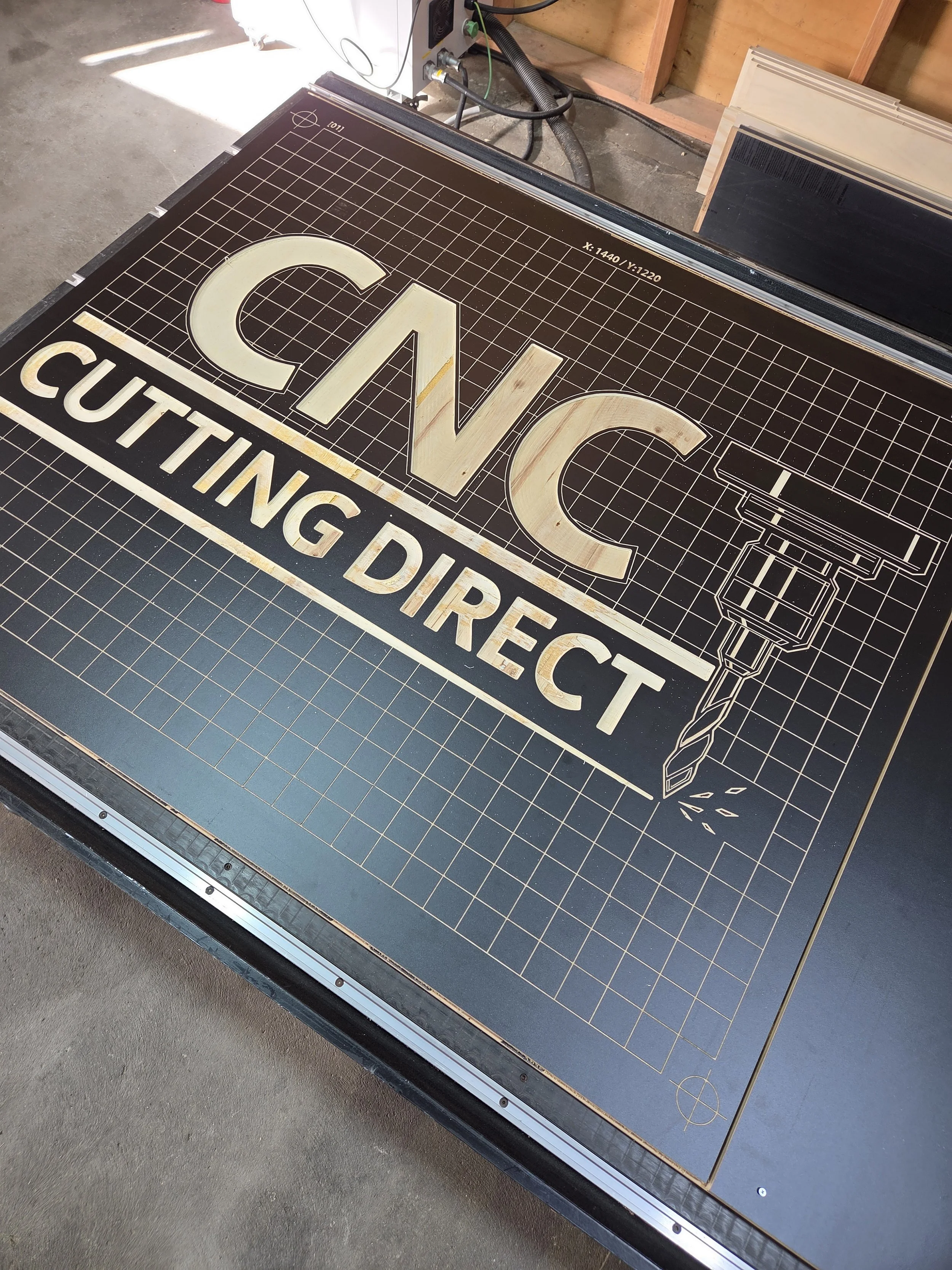 A laser cut sign reading 'CVC CUTTING DIRECT' with outlined letters and a graphic of a cutting tool, placed on a work table.