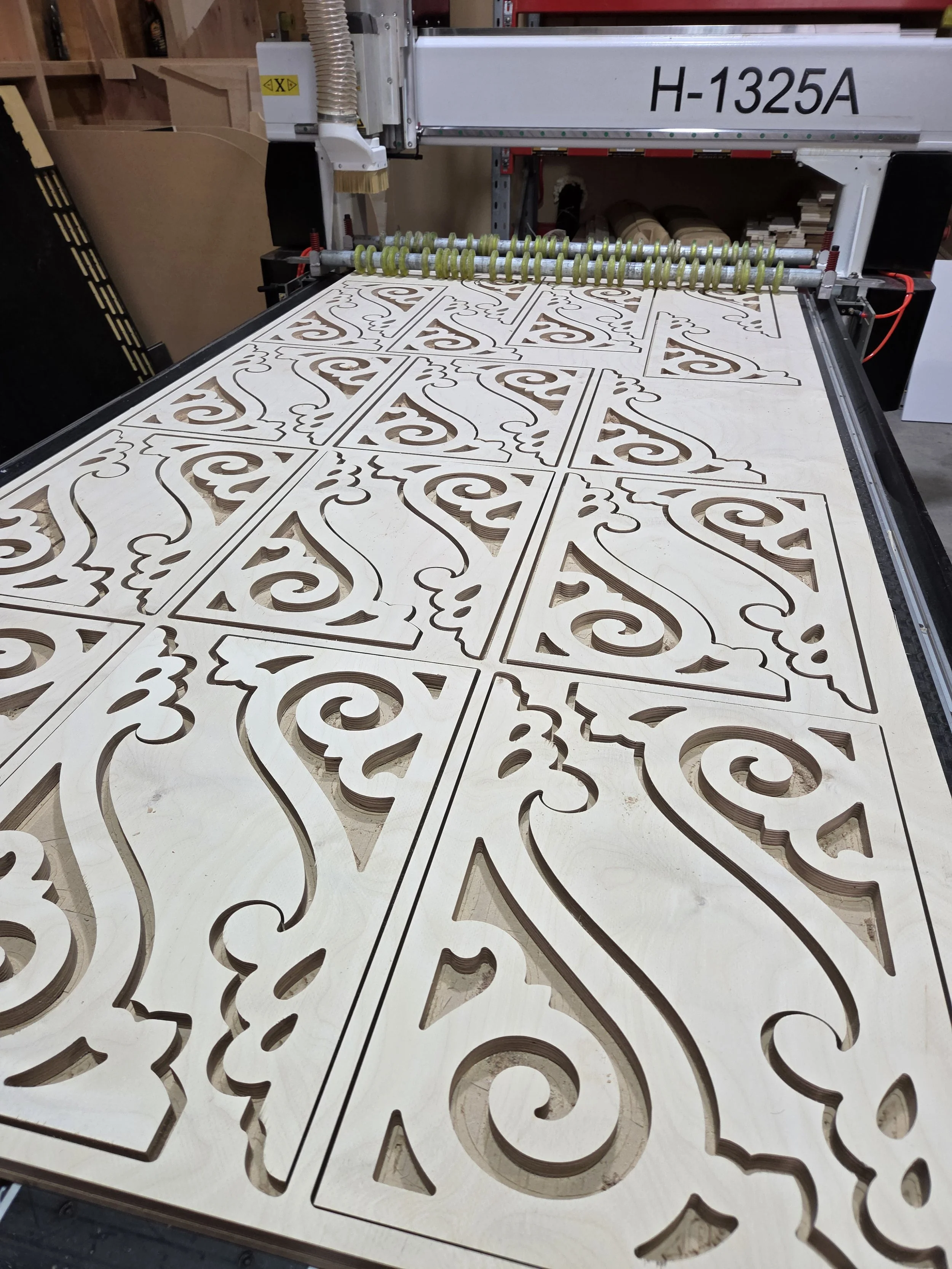Laser-cut wooden panels with ornate, symmetrical swirling designs, arranged on a flat surface.